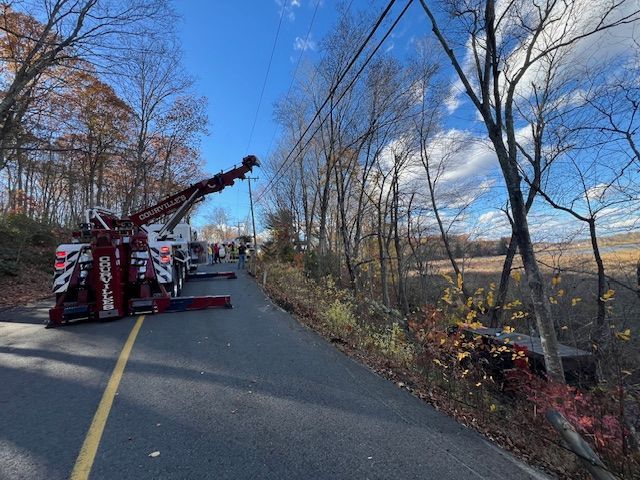 A tow truck on a road beside a wooded area, possibly clearing a scene.