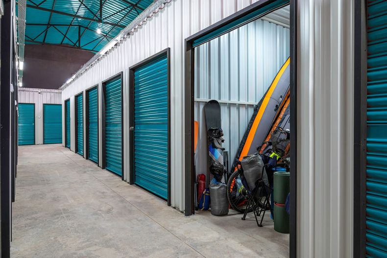 Storage unit hallway with turquoise doors and bikes stored beside a gray unit