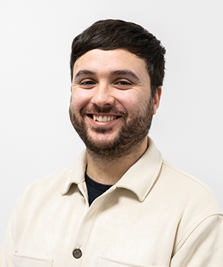 A man with a beard is smiling for the camera while wearing a white jacket.