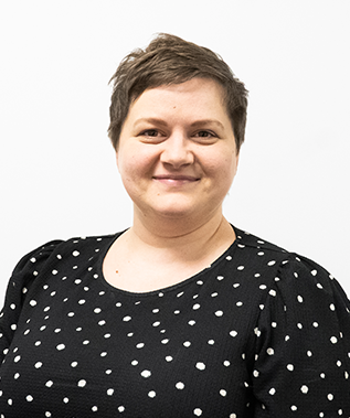 A woman wearing a black and white polka dot shirt is smiling for the camera.