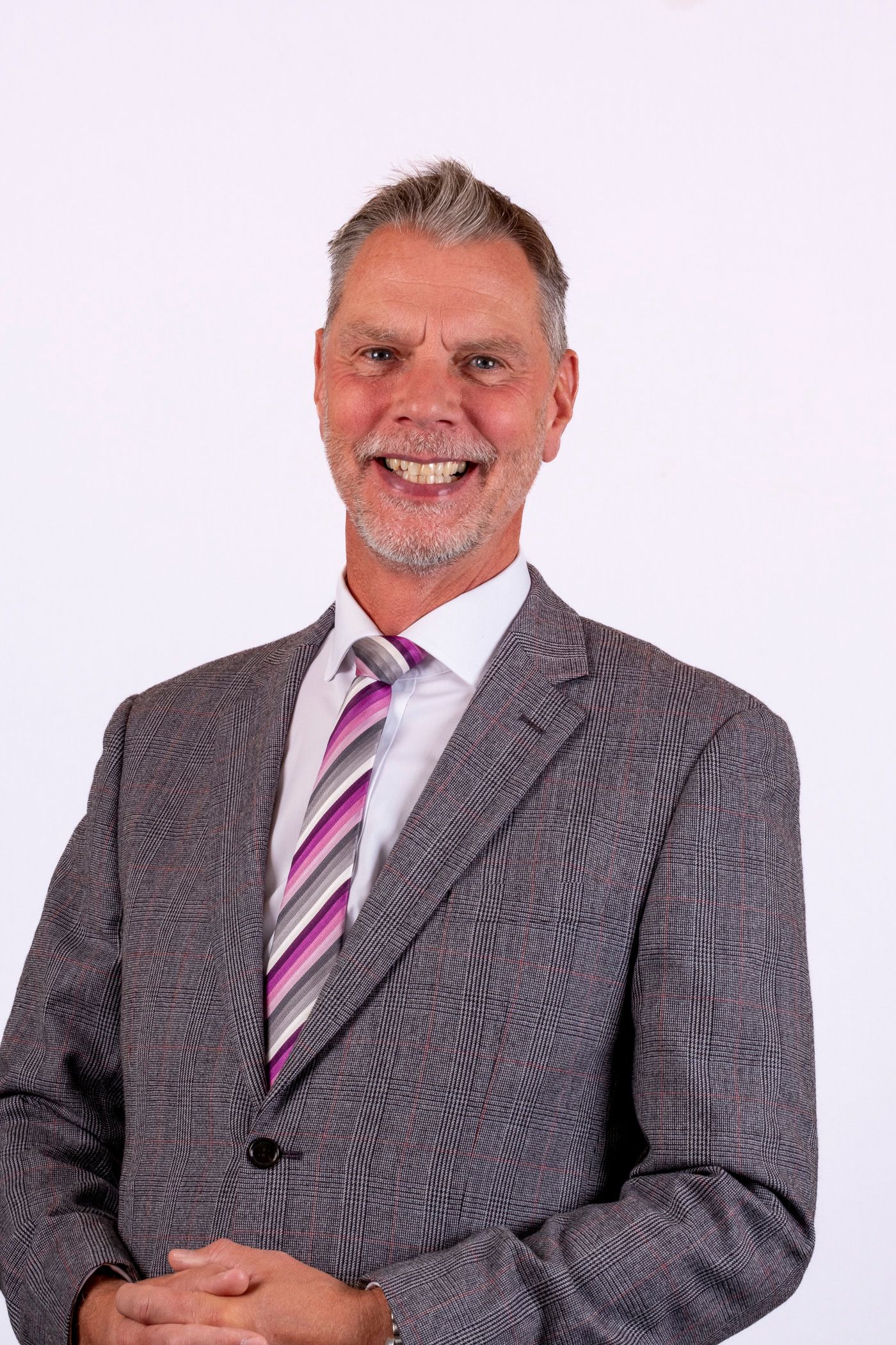 A woman with red hair is wearing a white shirt and smiling.