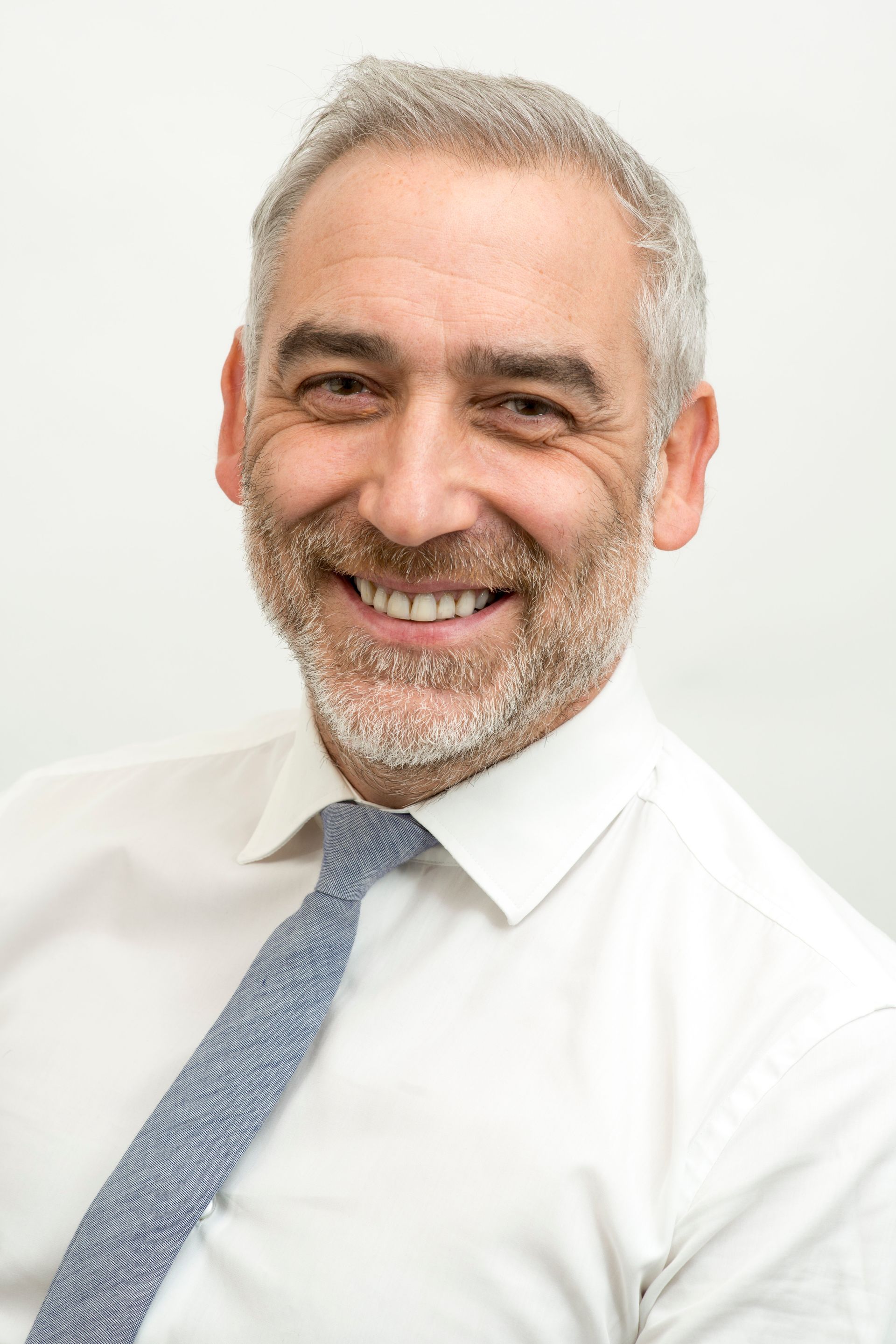 A man in a suit and tie is smiling in front of a building.