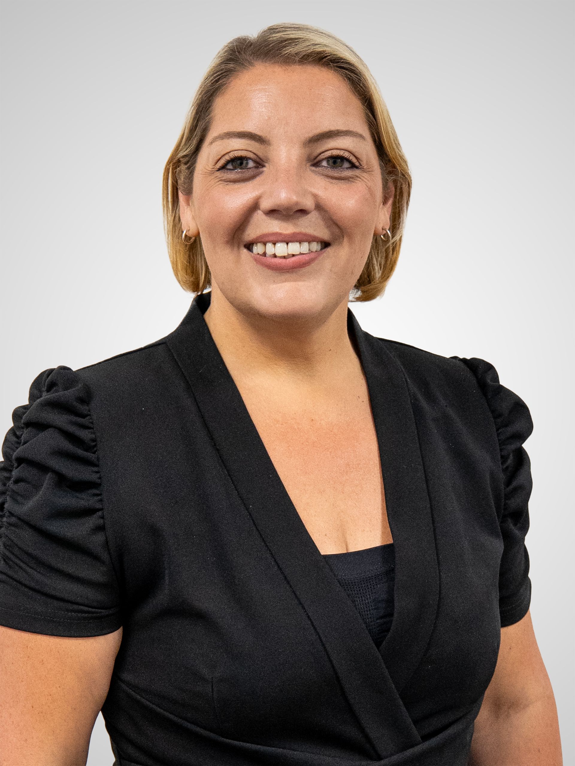 A woman wearing a feather print shirt and a necklace is smiling for the camera.