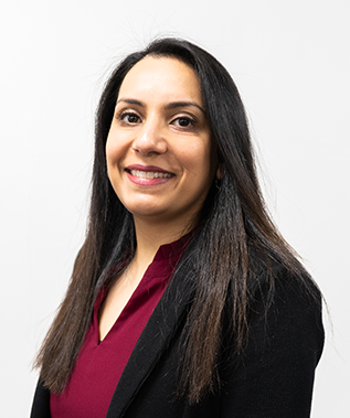 A woman in a red shirt and black jacket is smiling for the camera.