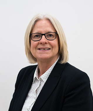 A woman wearing glasses and a black jacket is smiling for the camera.