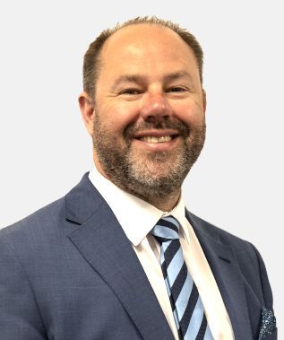A man in a suit and tie is smiling for the camera.