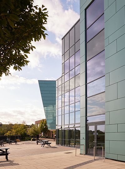 A large building with a lot of windows has a picnic table in front of it