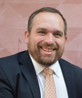 A man in a suit and tie is smiling for the camera