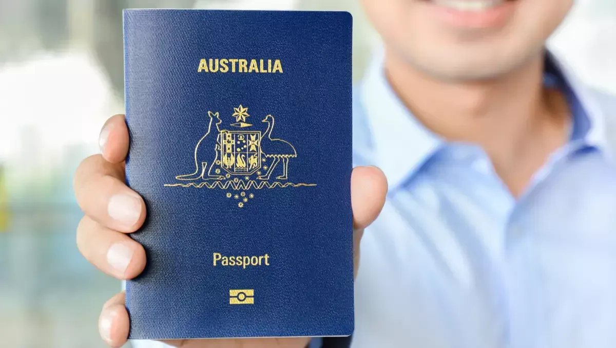 Um homem está segurando um passaporte australiano azul na mão.