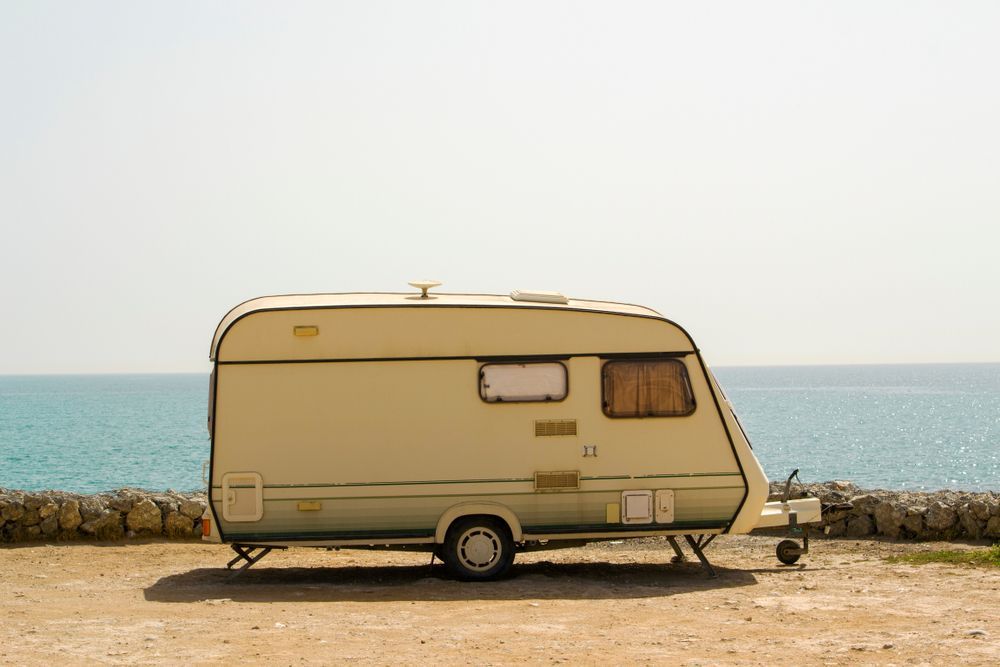 Beige Camper Van Parked by the Sea on a Sandy Shore Under a Pale Sky — Edmonton Battery Centre in Gordonvale, QLD