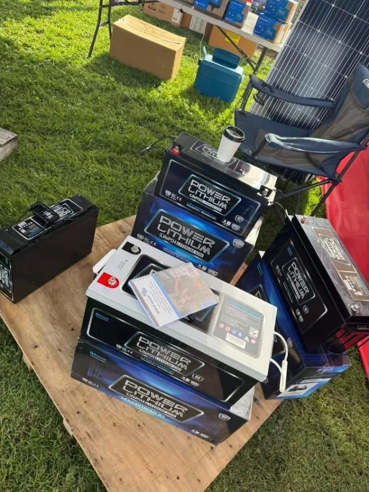 Batteries Stacked Outdoors on a Wooden Surface, With a Box and Solar Panels — Edmonton Battery Centre in Bentley Park, QLD