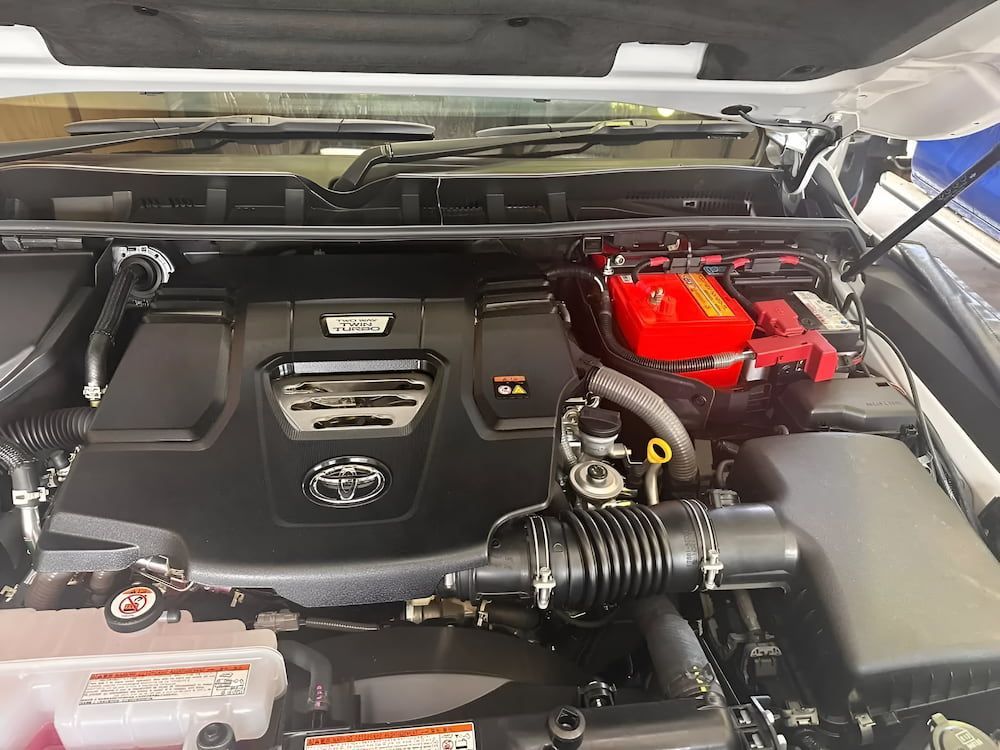 Car Engine Bay With Black Cover, Red Battery, and Various Components — Edmonton Battery Centre in Bentley Park, QLD