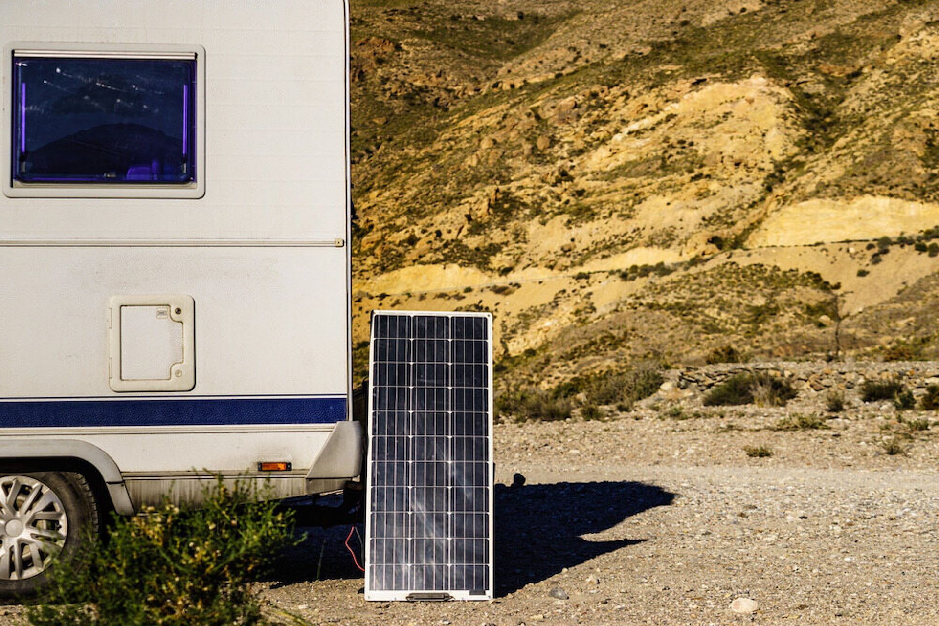 White Camper Van With a Solar Panel Leaning Against It in a Rocky Desert Landscape — Edmonton Battery Centre in Woree, QLD
