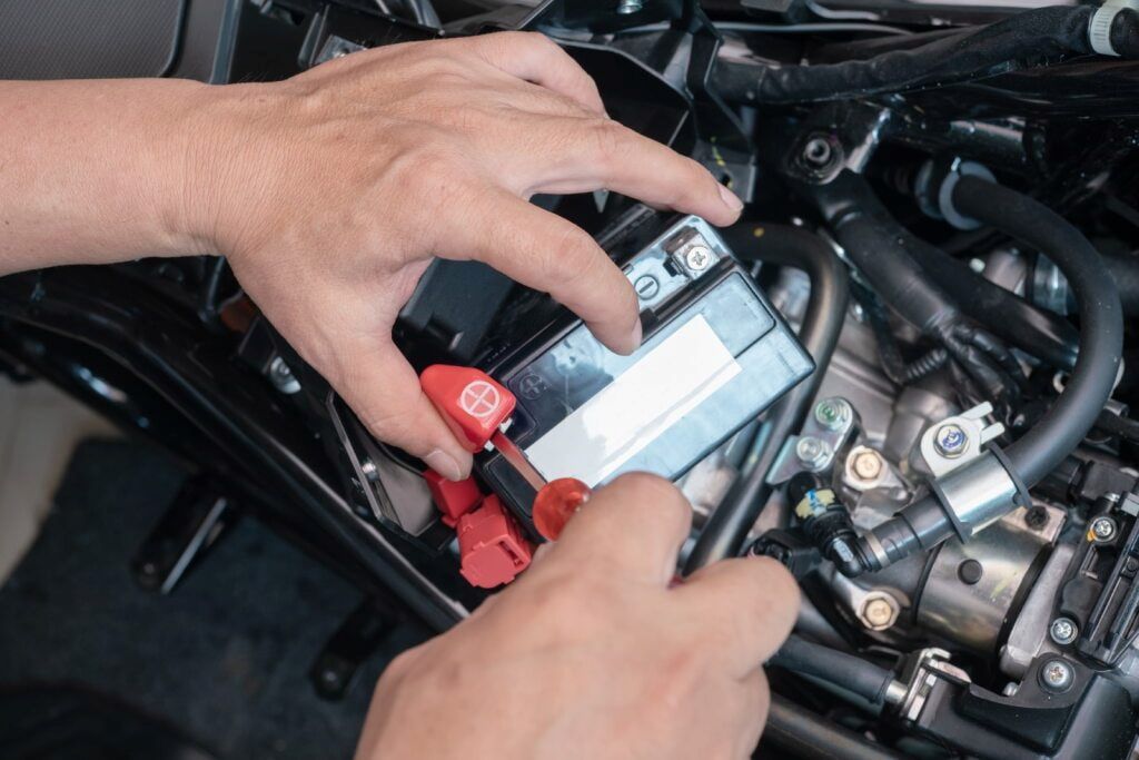 Hands Removing a Motorcycle Battery Terminal With a Screwdriver — Edmonton Battery Centre in Bentley Park, QLD