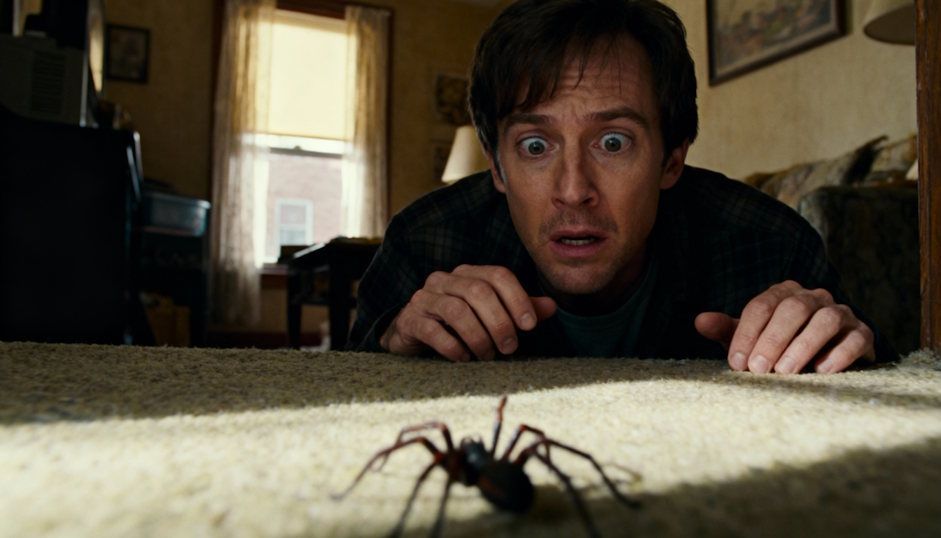 Man anxiously staring at a spider in a Cleveland apartment strong fear reaction visible