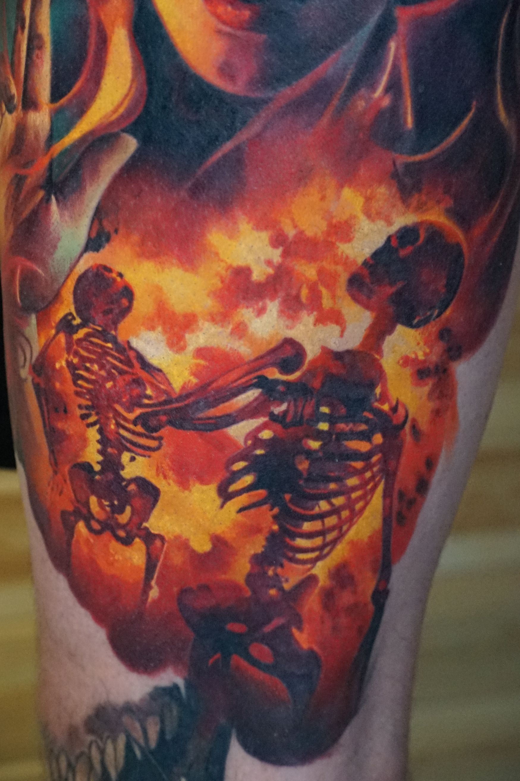 A close up of a tattoo of a woman and skeletons on a person 's leg.