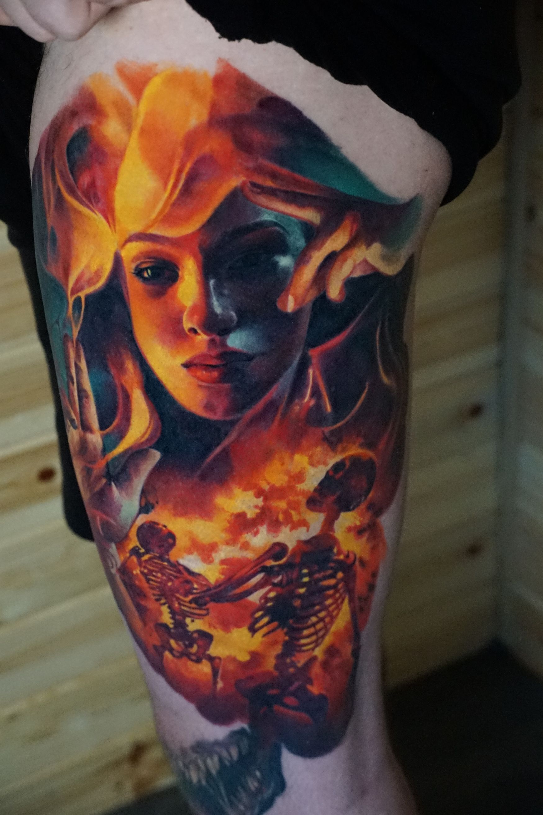 A colorful tattoo of a woman 's face and a skeleton on a person 's leg.
