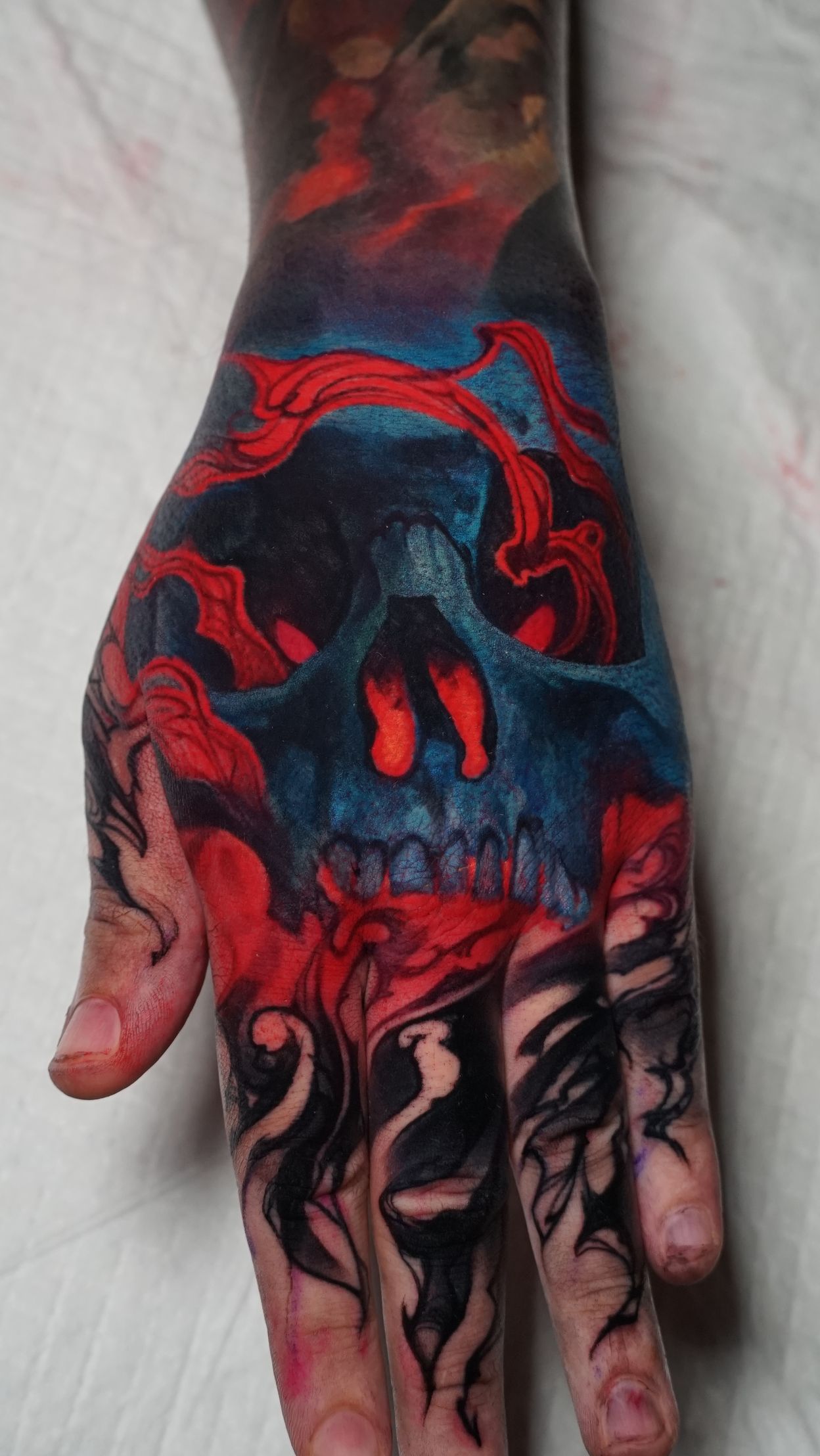 A close up of a person 's hand with a skull tattoo on it.