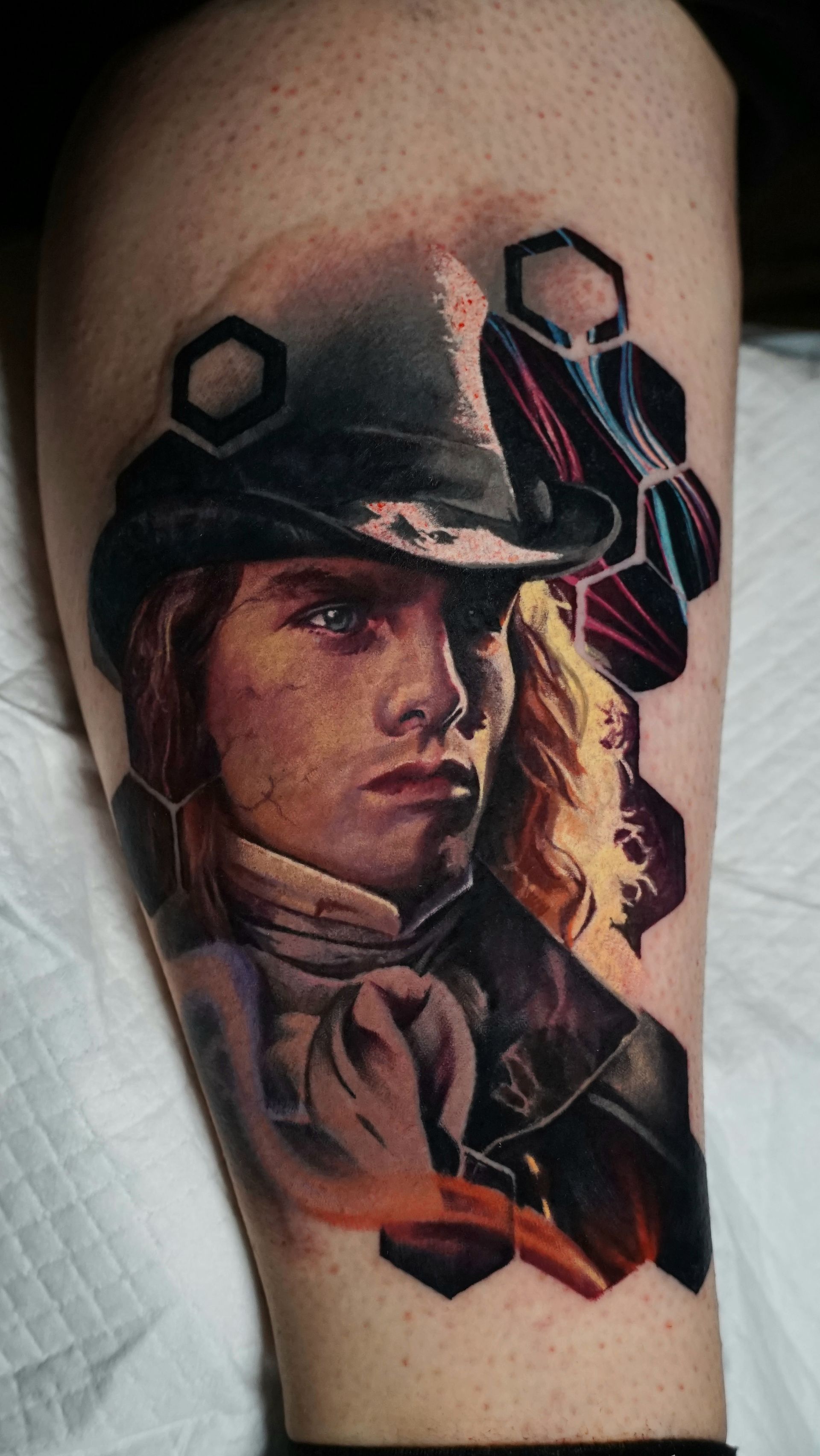A tattoo of a man in a top hat and tie on a leg.