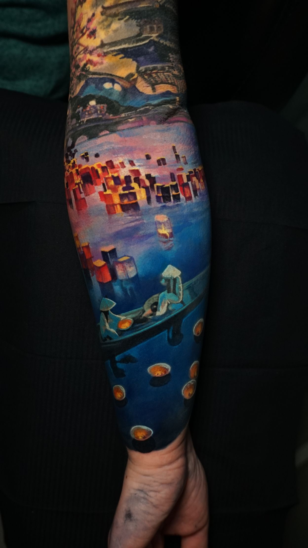 A person has a tattoo on their arm of a painting of a boat.