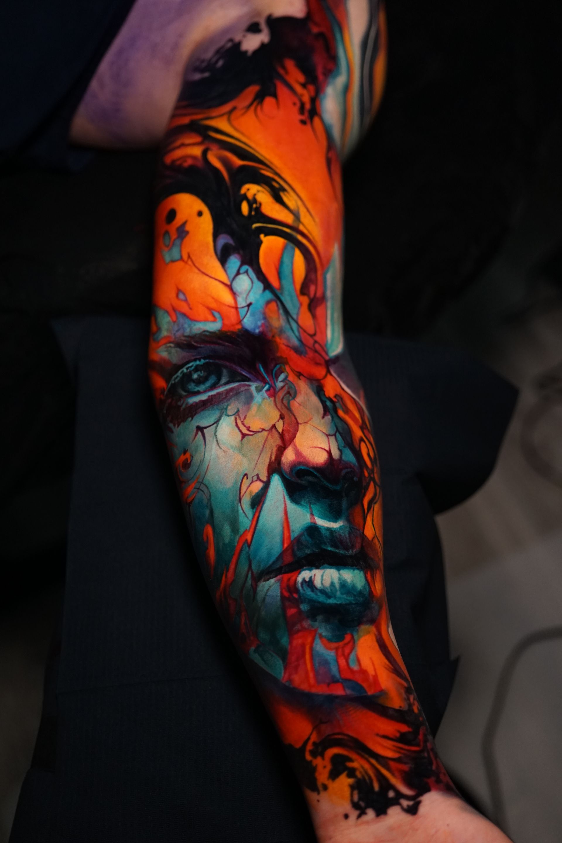 A person has a colorful tattoo of a woman 's face on their arm.