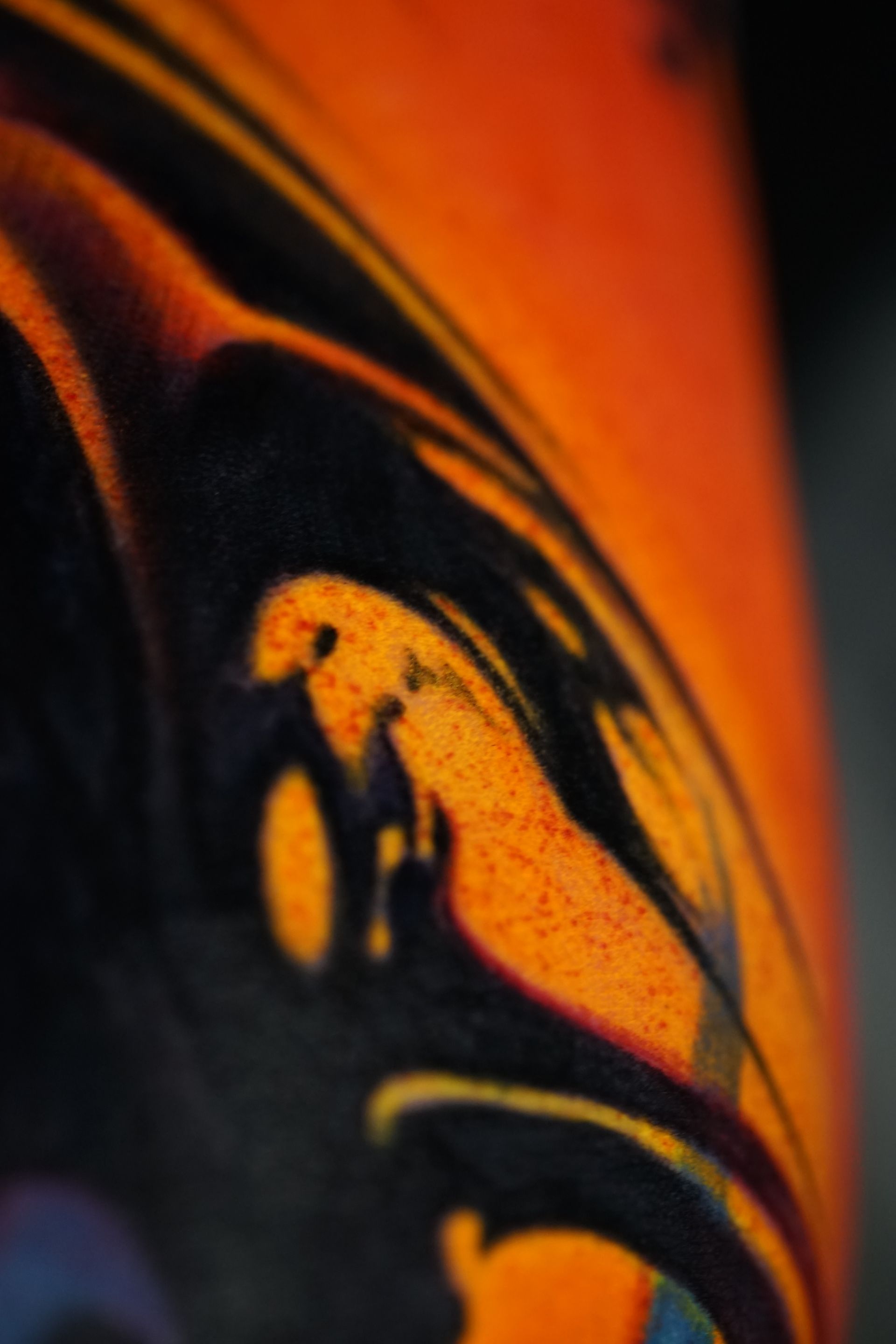 A close up of an orange and black painting on a wall.