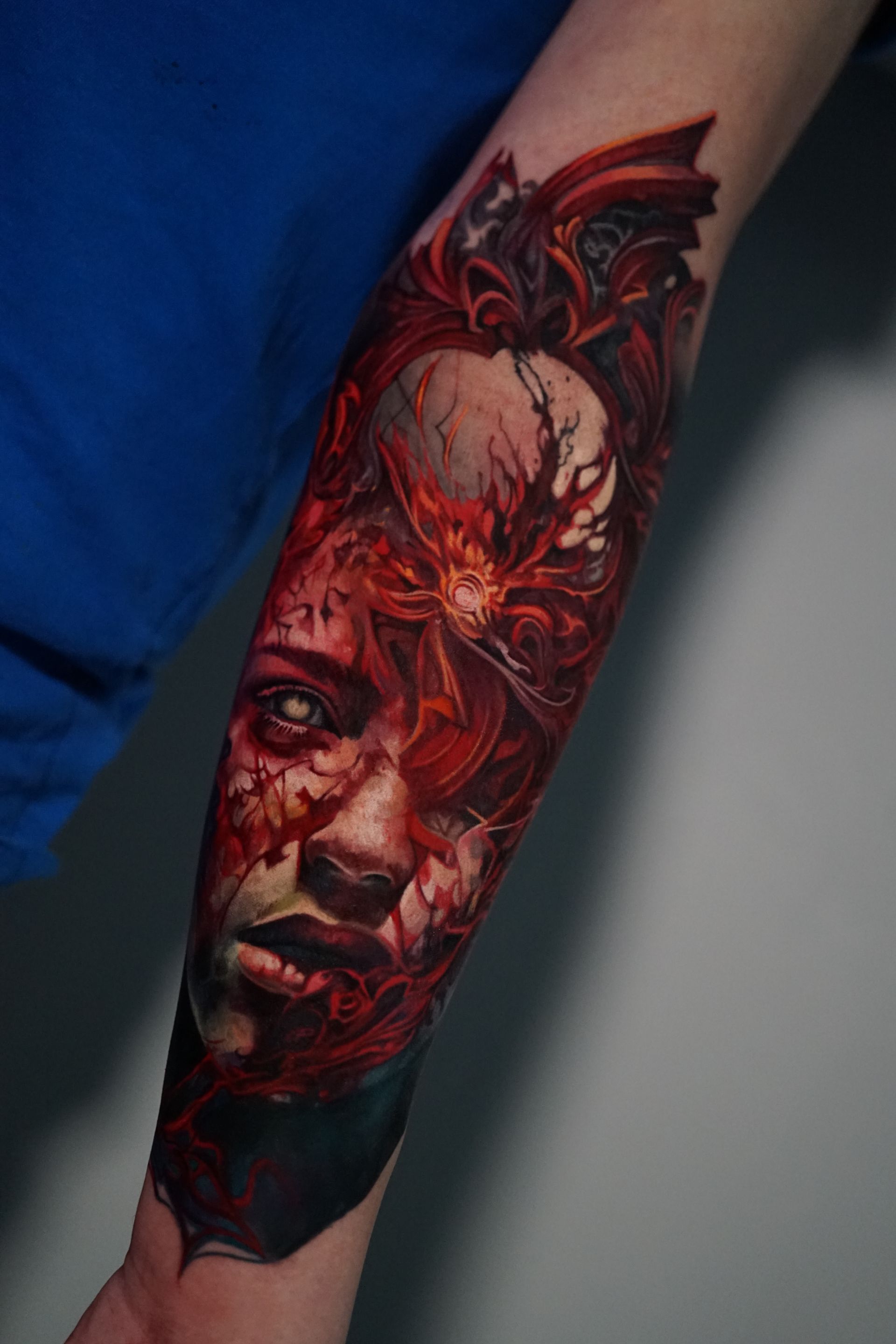 A tattoo of a woman 's face with a dragon on her forearm.