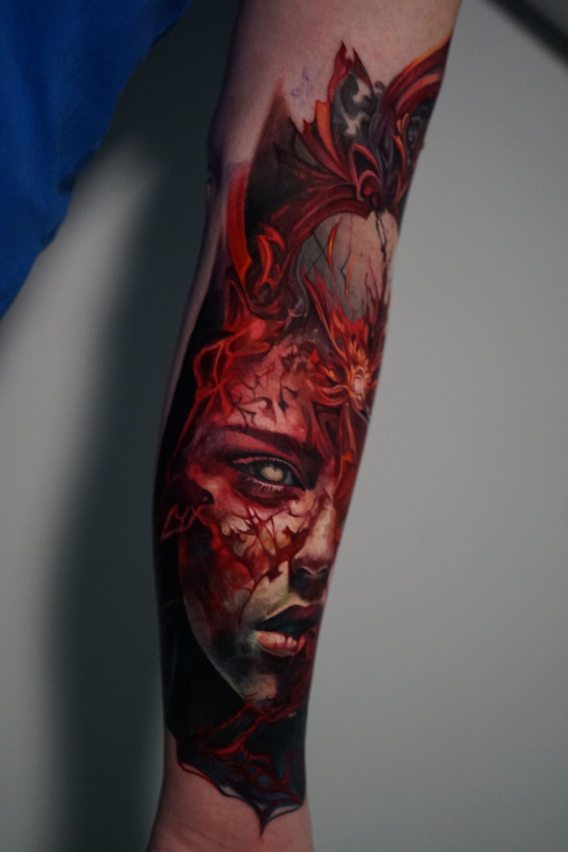 A tattoo of a woman 's face with a bat on her forearm.