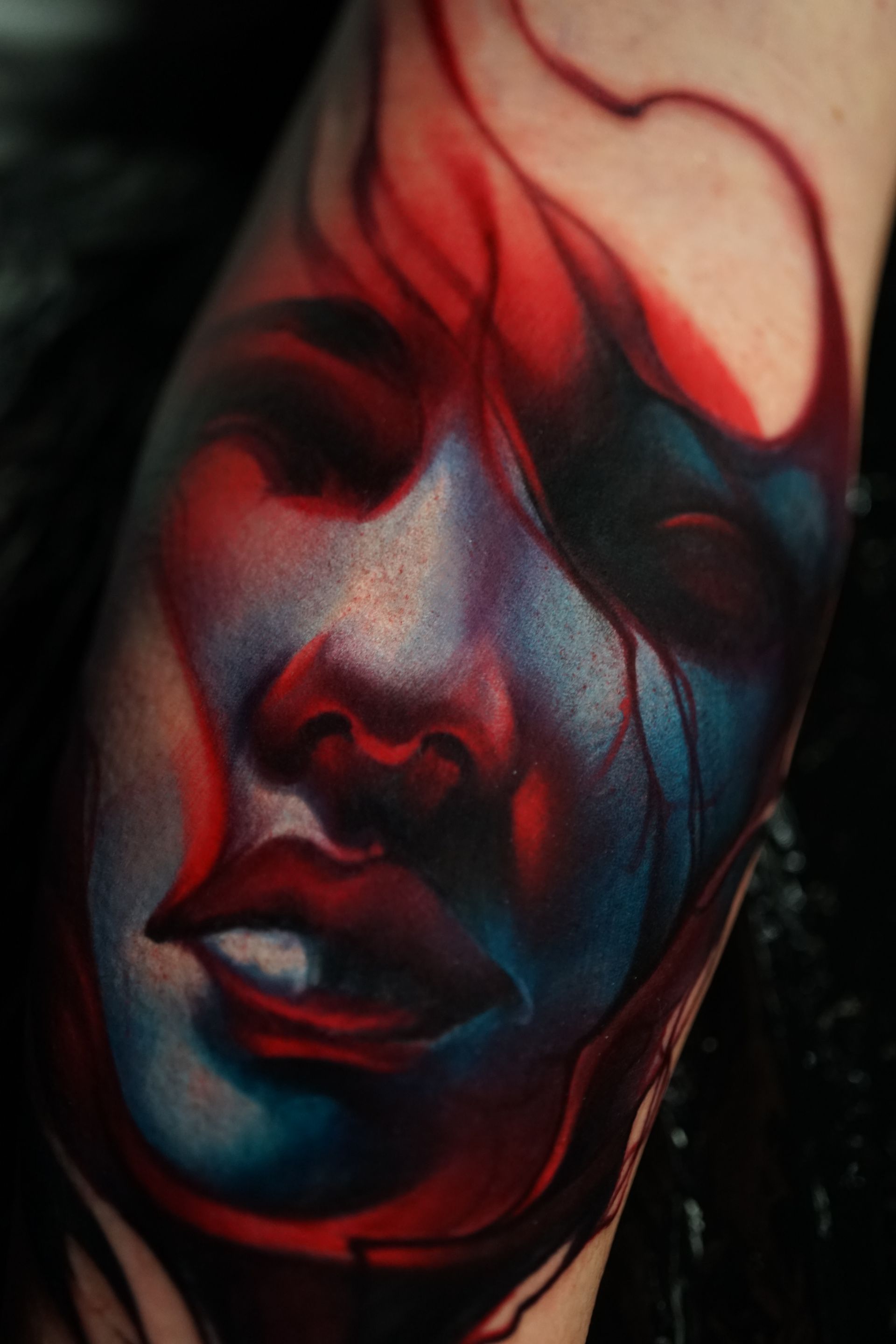 A close up of a colorful tattoo of a woman 's face on a person 's arm.