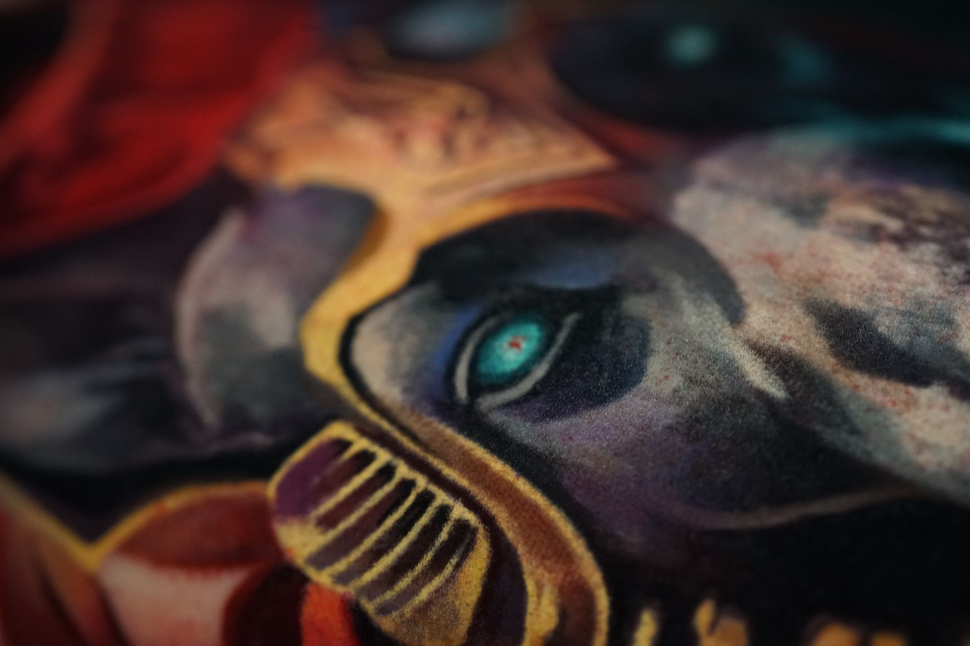 A close up of a painting of a clown with blue eyes.