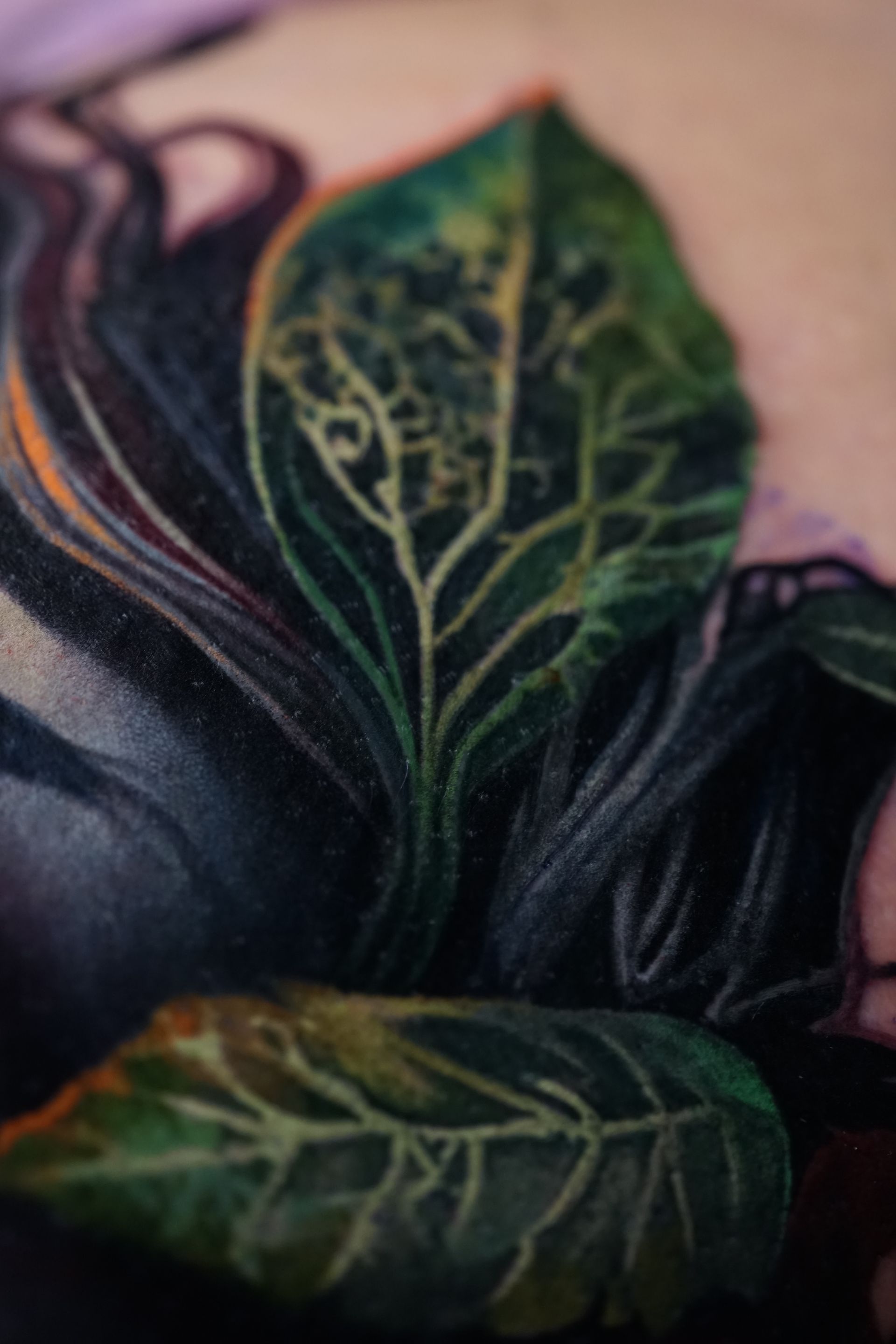 A close up of a tattoo of a leaf on a person 's arm.