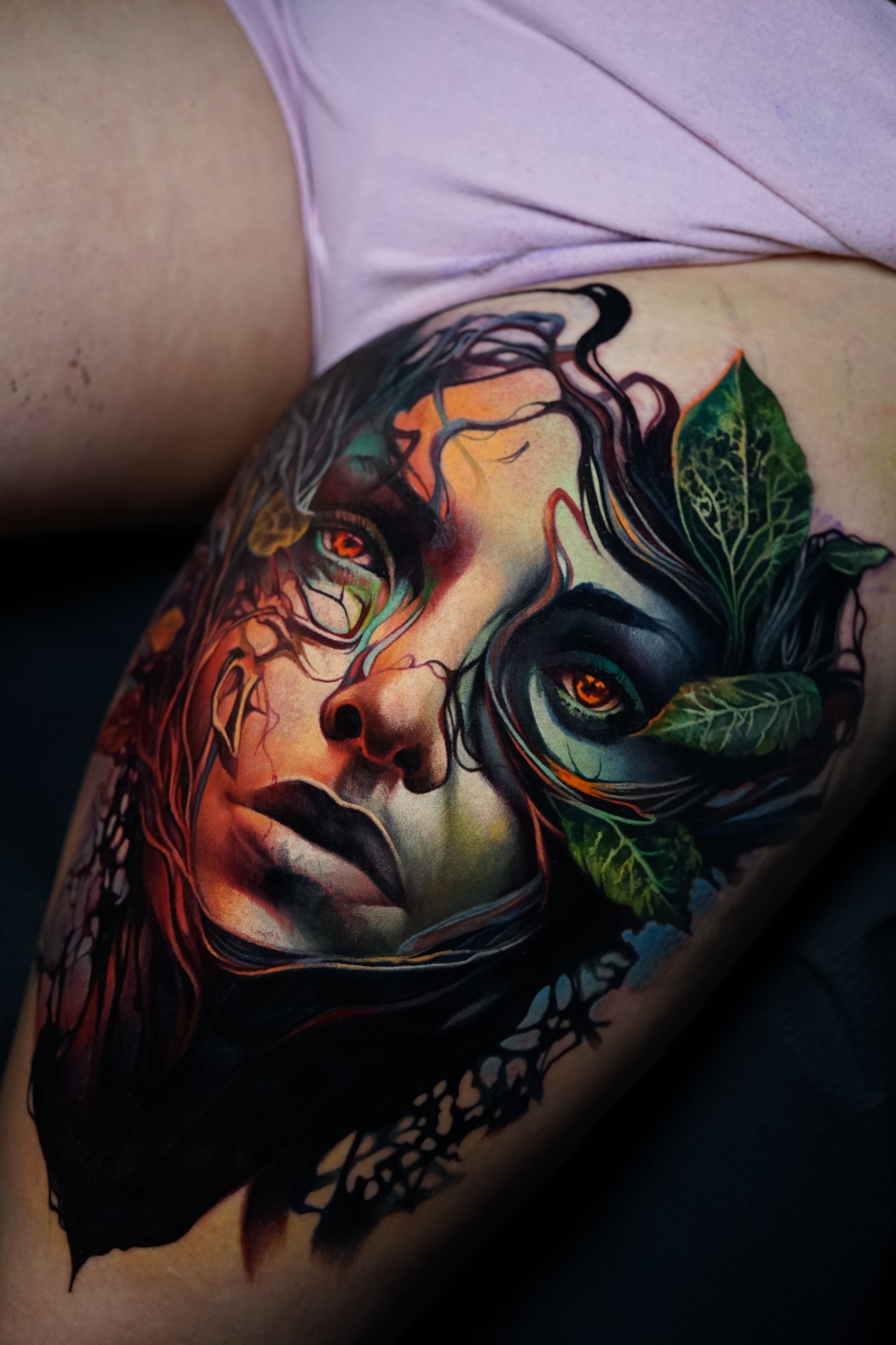 A woman has a colorful tattoo of a woman 's face on her leg.