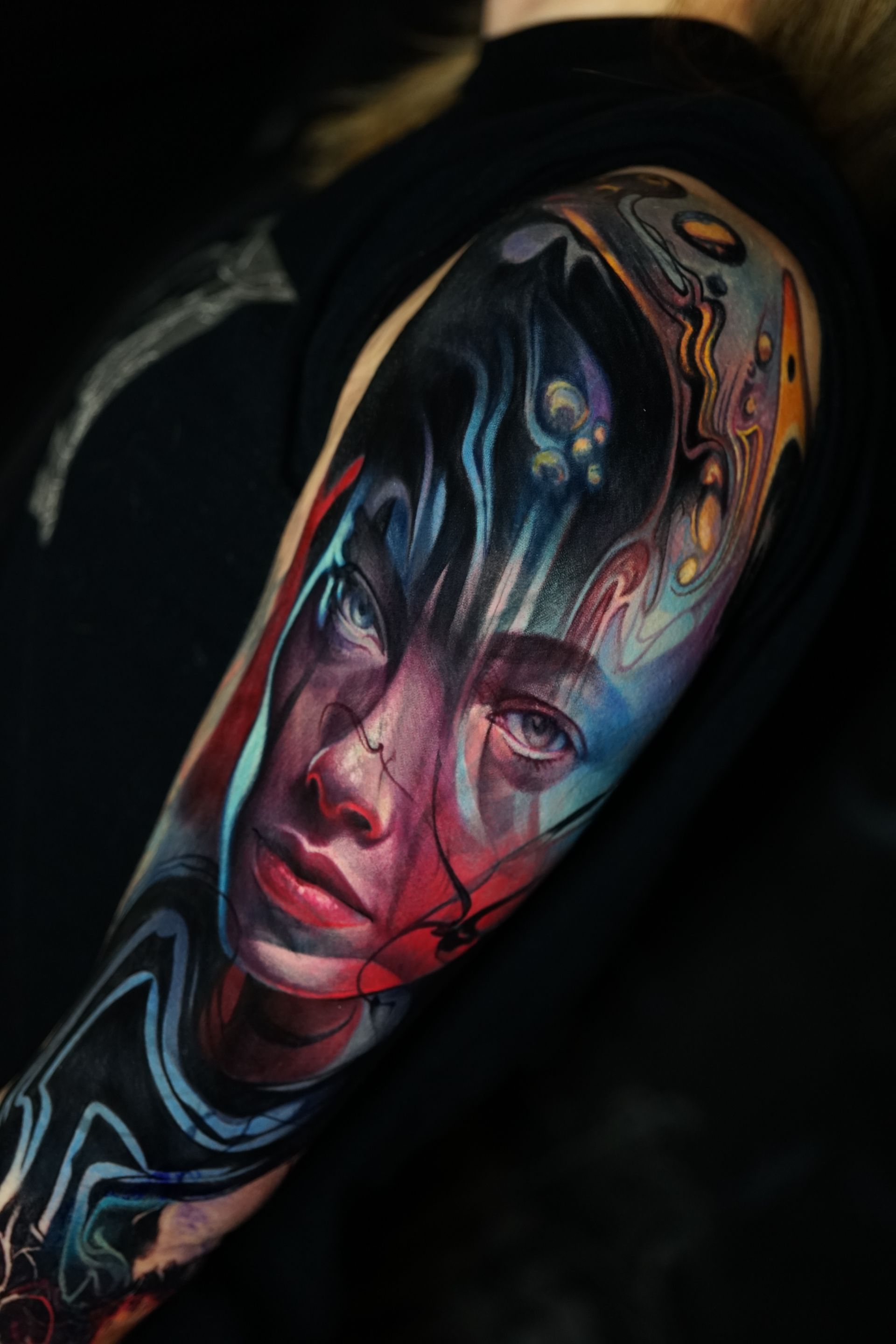 A woman has a colorful tattoo of a woman 's face on her arm.