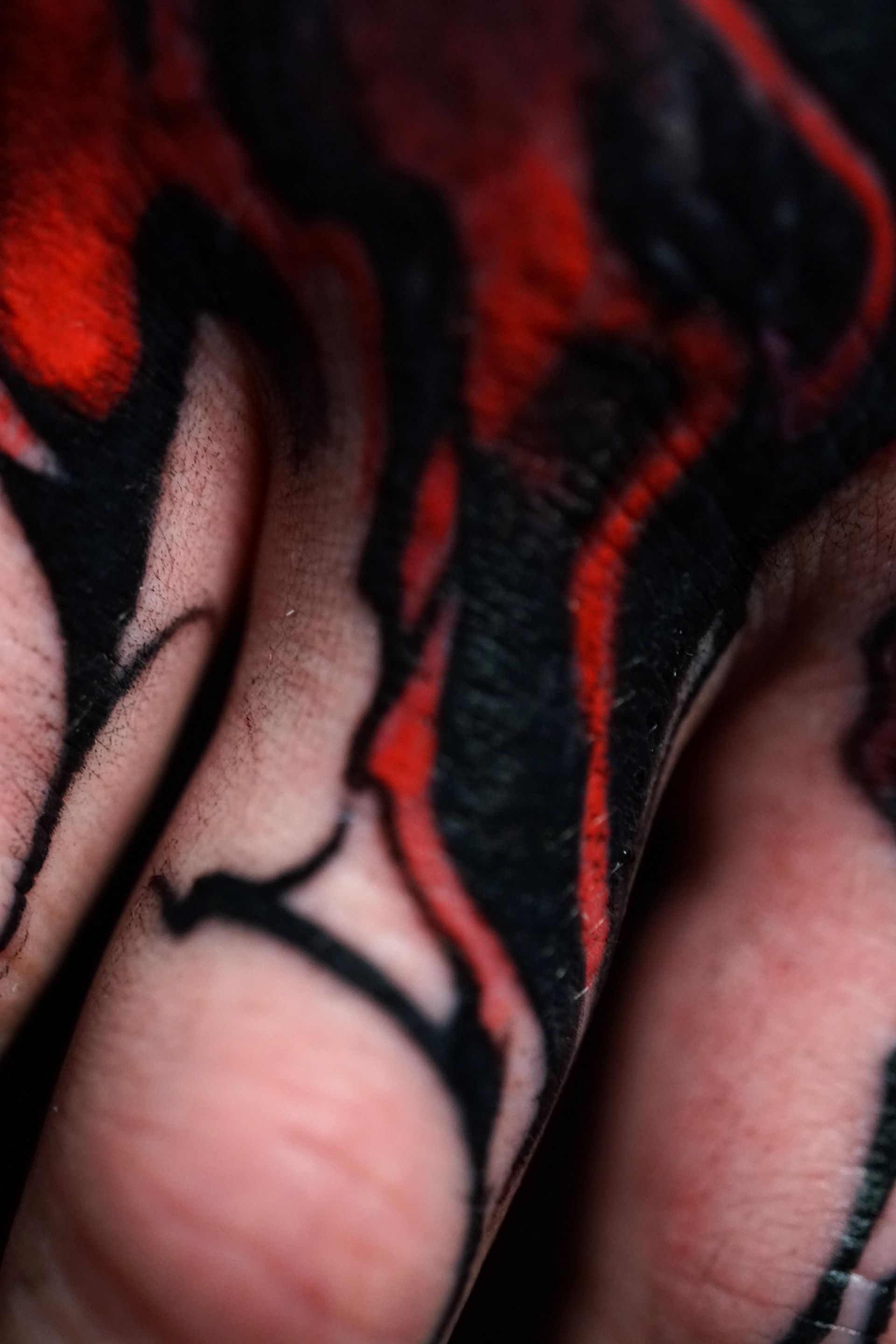 A close up of a person 's fingers with a red and black tattoo on them.