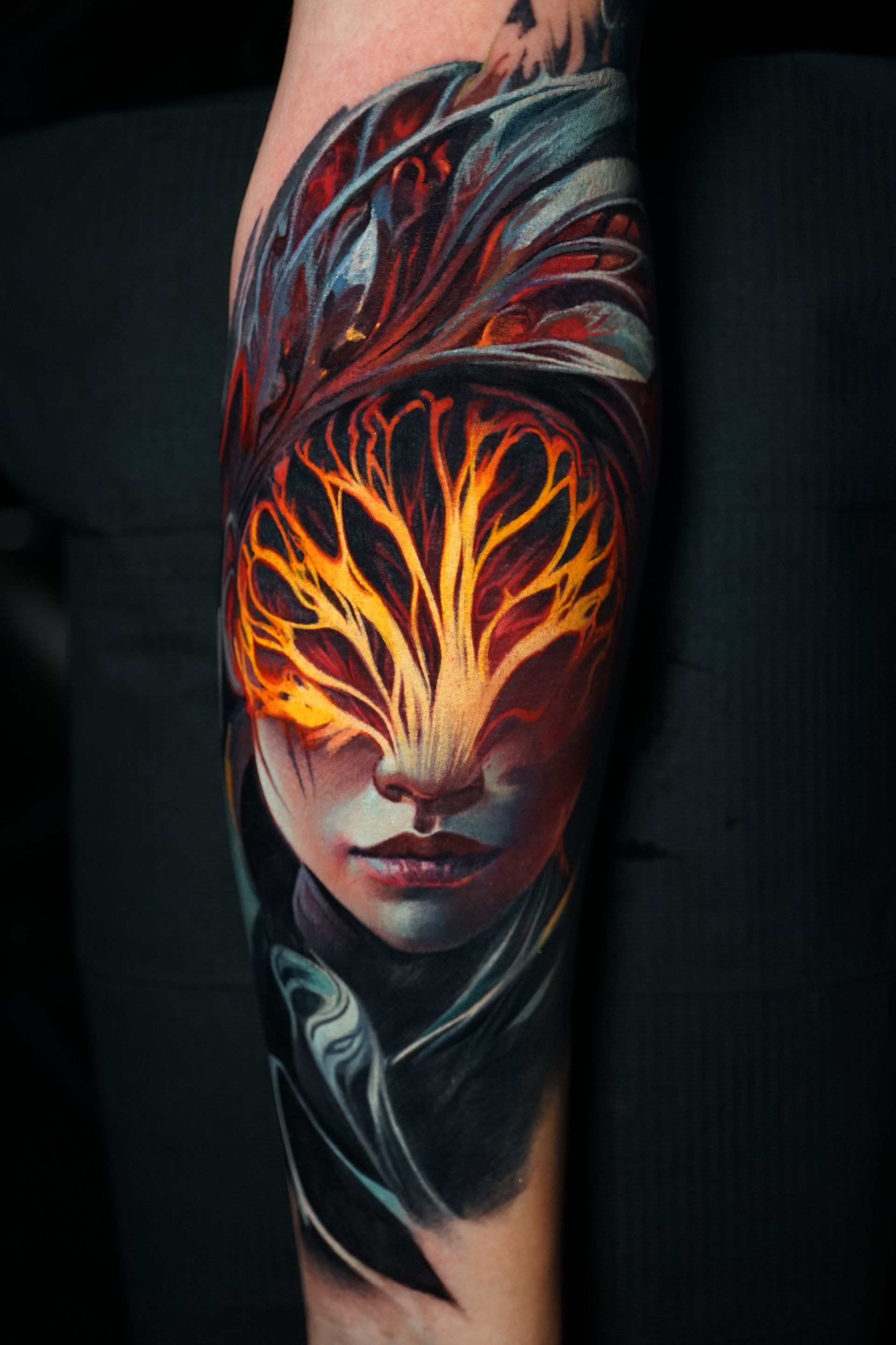A colorful tattoo of a woman 's face with a tree in her eyes.