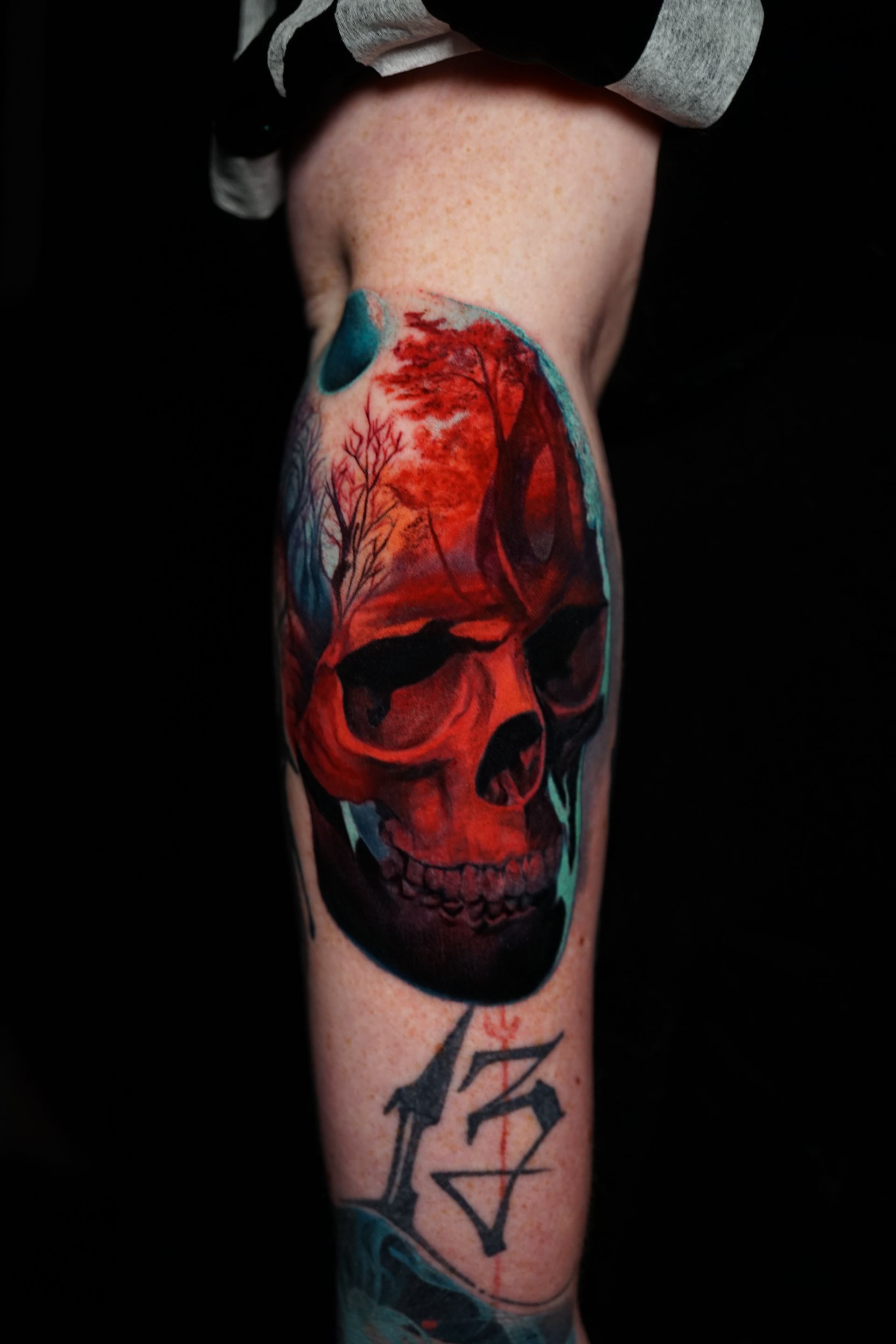 A person has a colorful skull tattoo on their leg.
