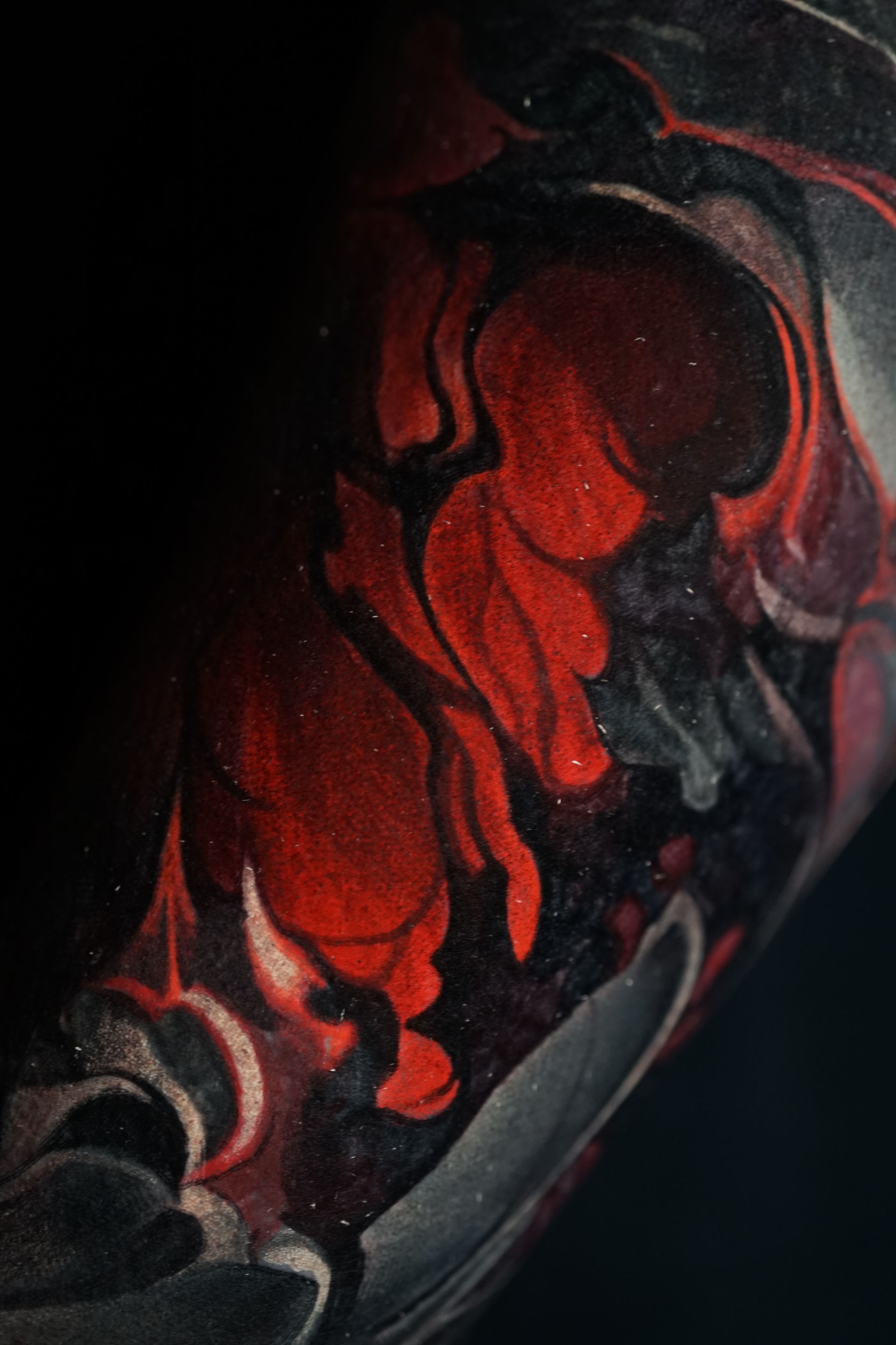 A close up of a red and black painting on a black background.