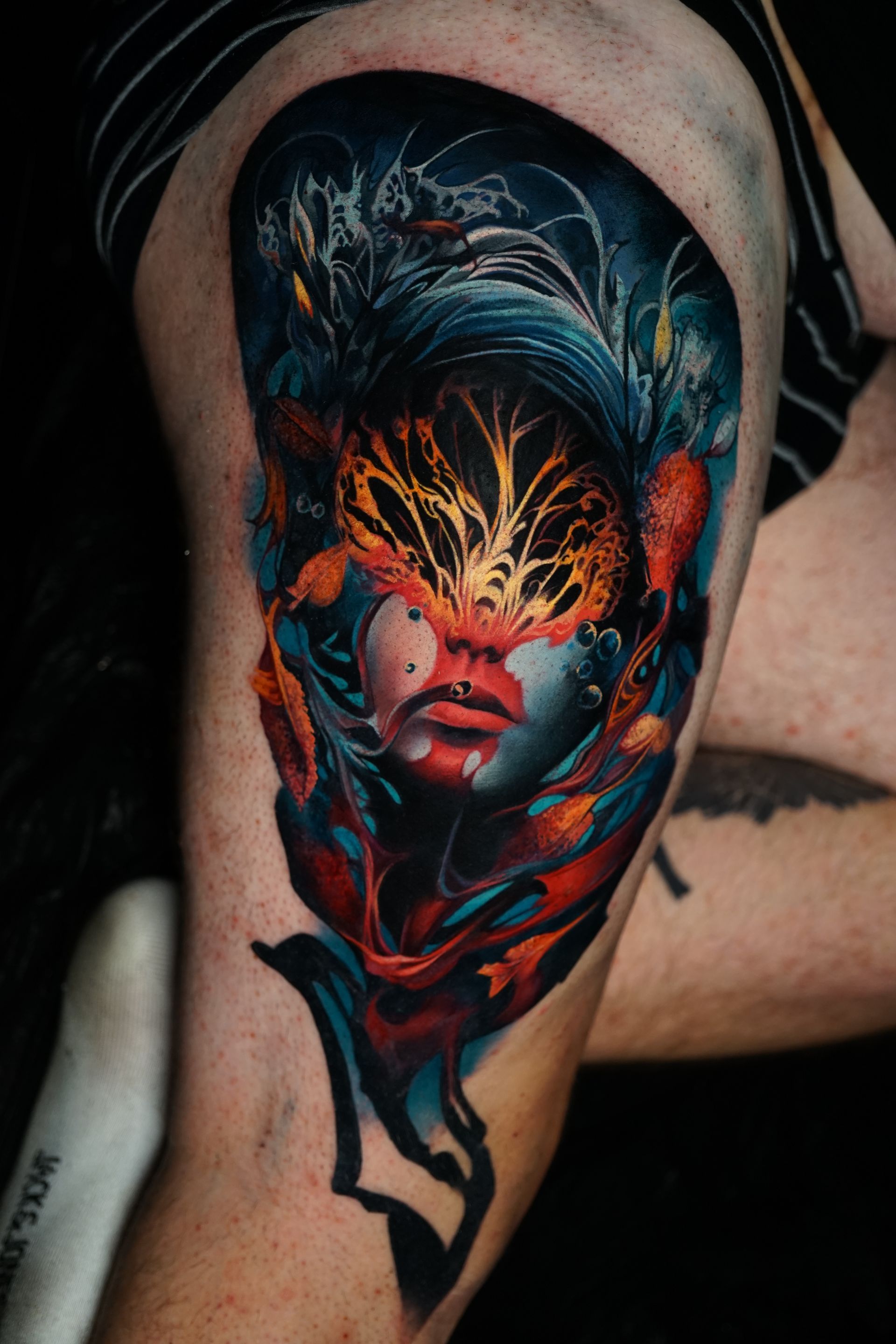 A person has a colorful tattoo of a woman 's face on their leg.