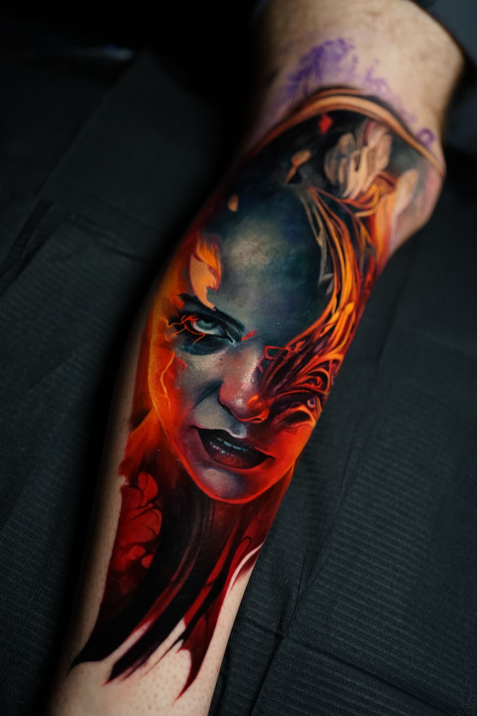 A person has a tattoo of a woman 's face on their leg.