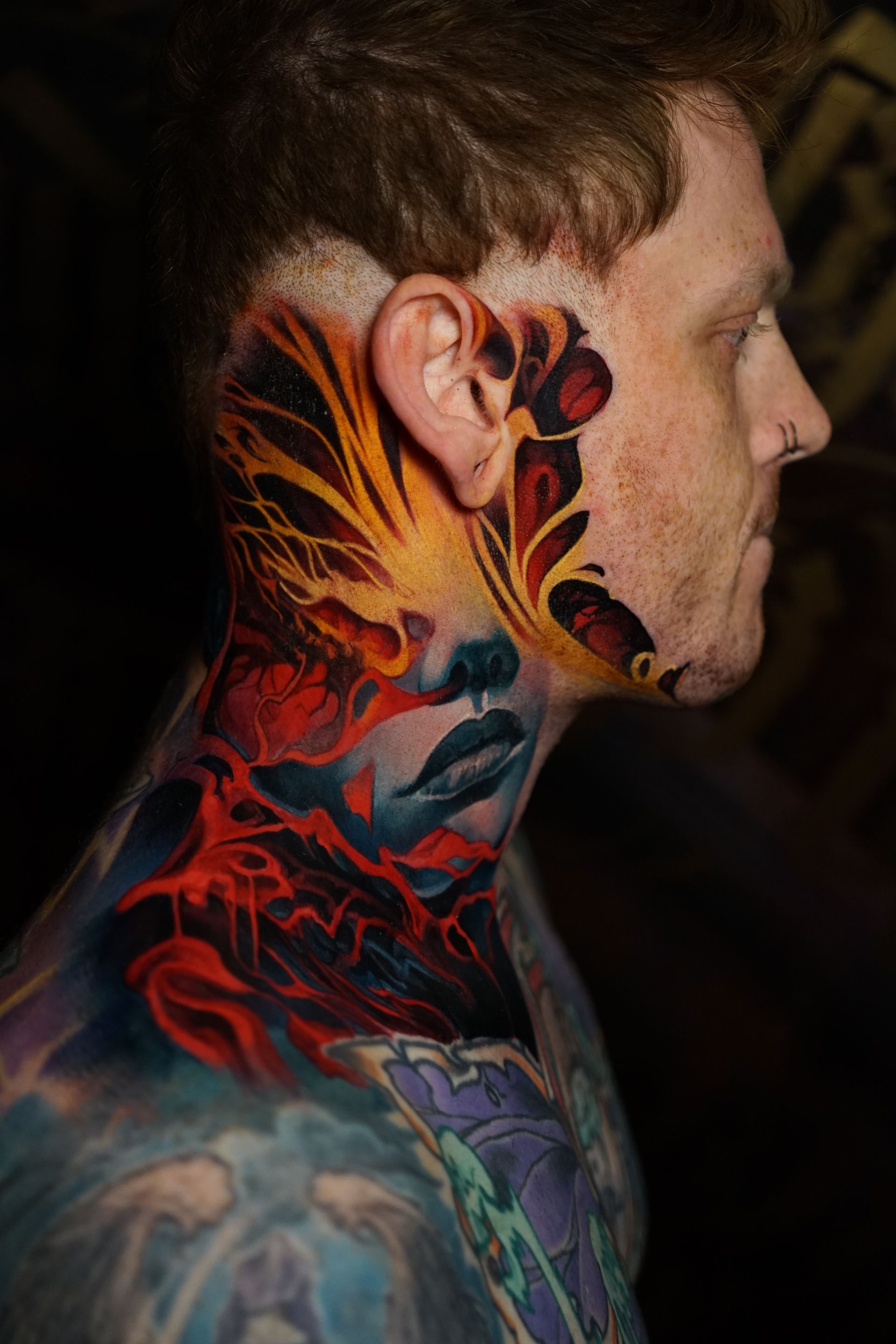 A man with a tattoo on his face and neck.