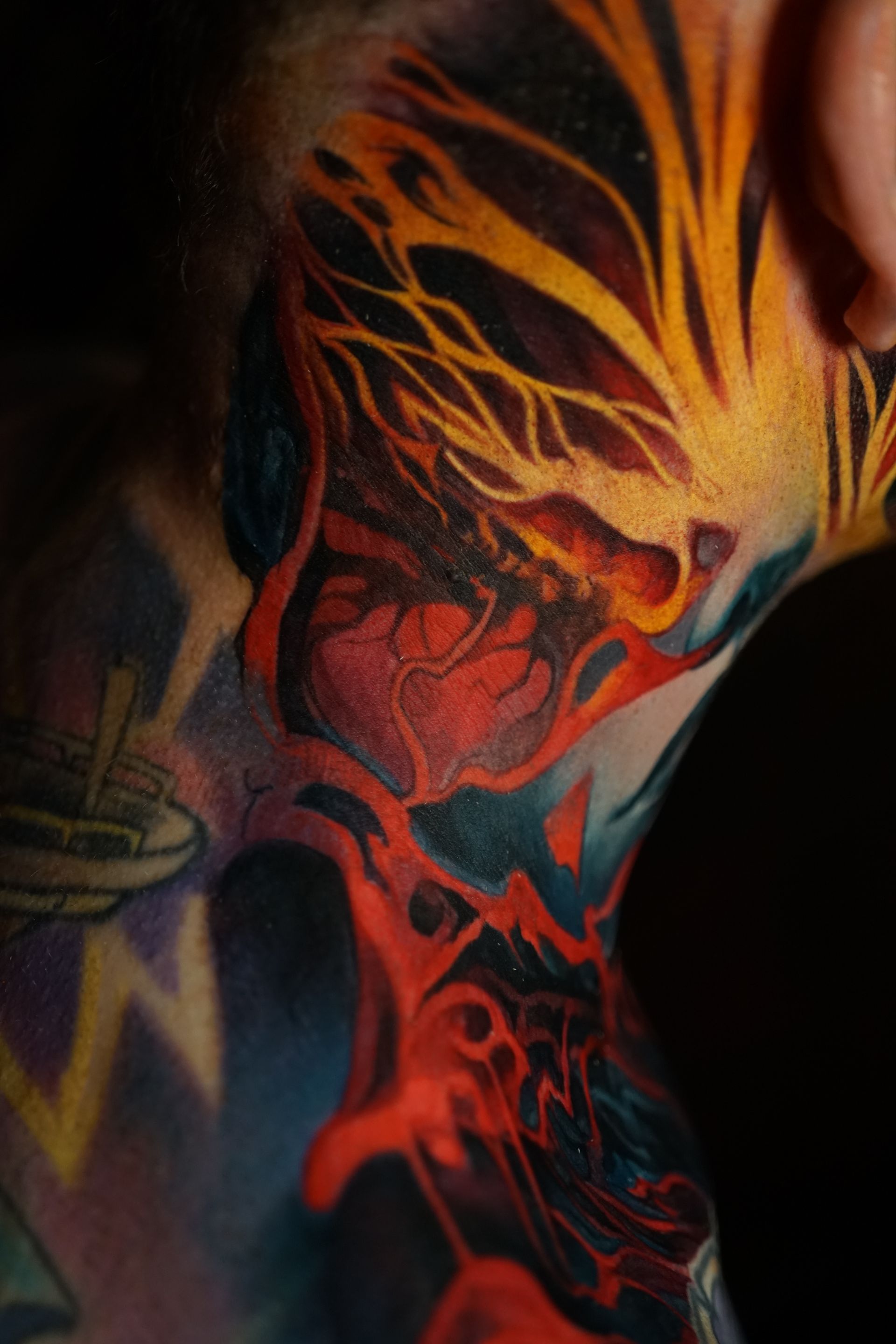 A man has a colorful tattoo on his face and neck