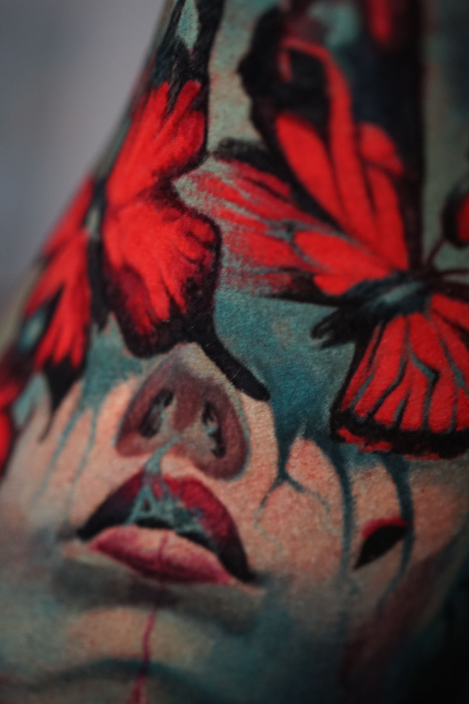 A close up of a tattoo of a woman 's face with red butterflies.