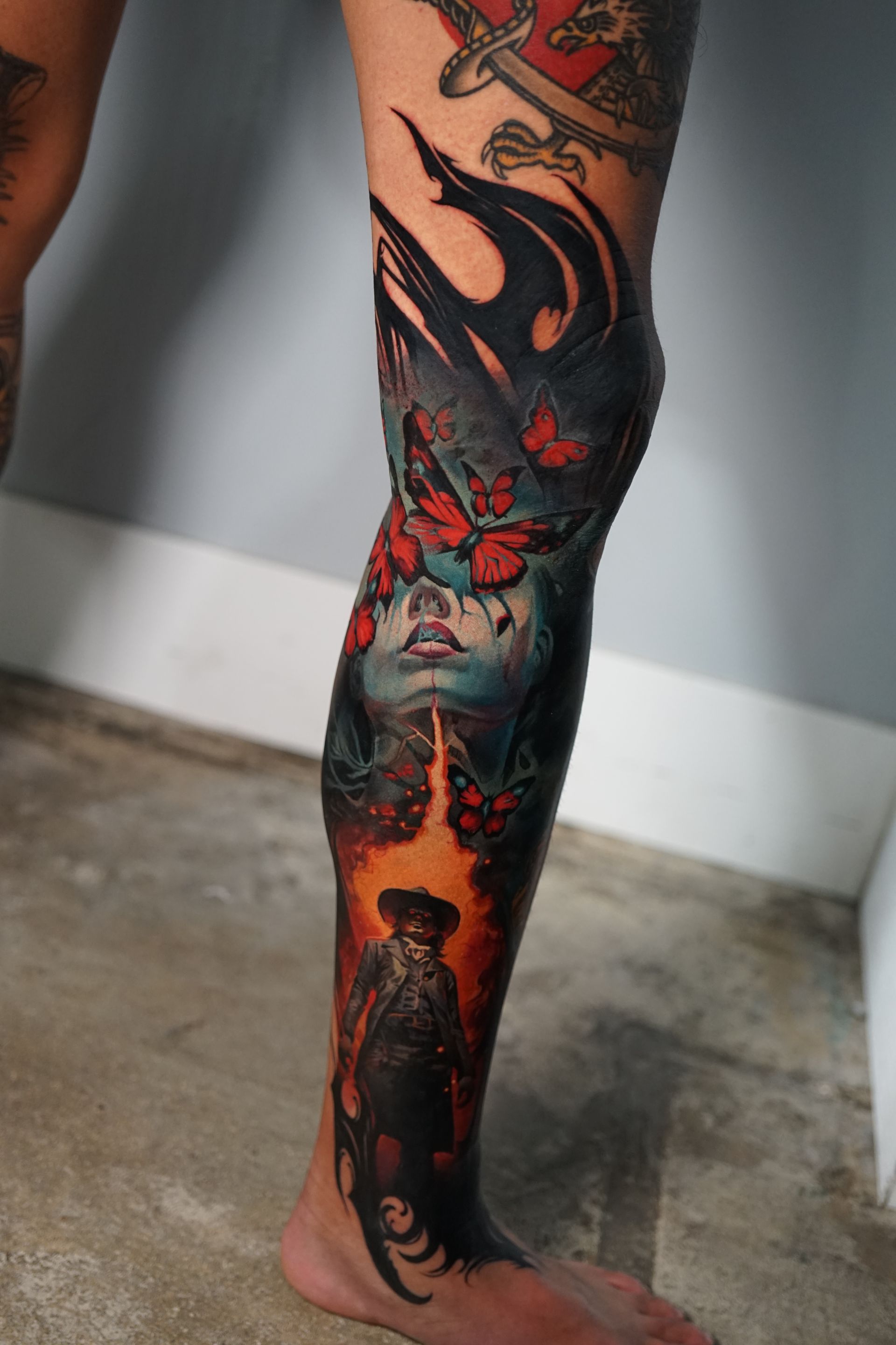 A person has a tattoo on their leg that looks like a painting