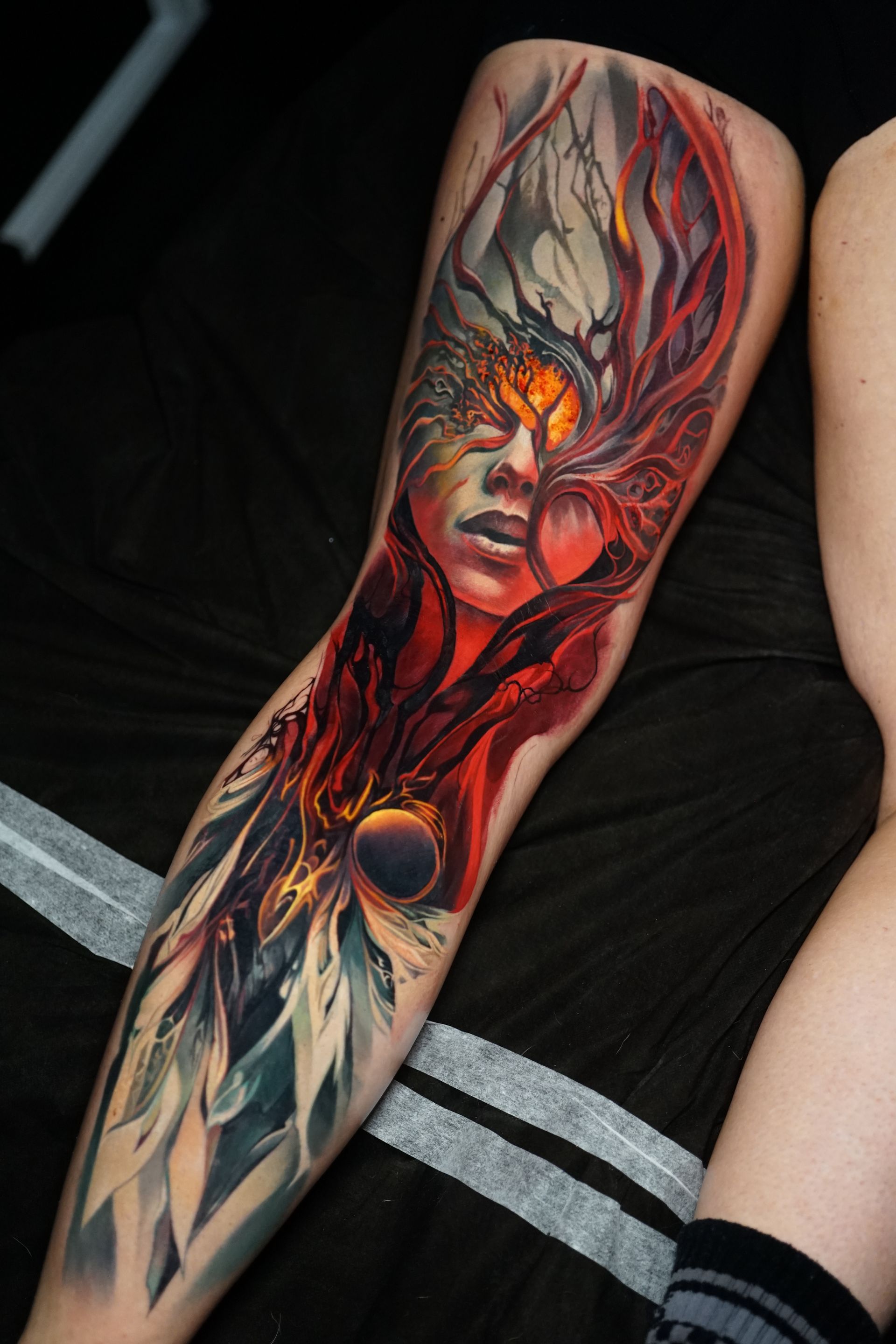 A woman has a tattoo of a woman 's face on her leg.