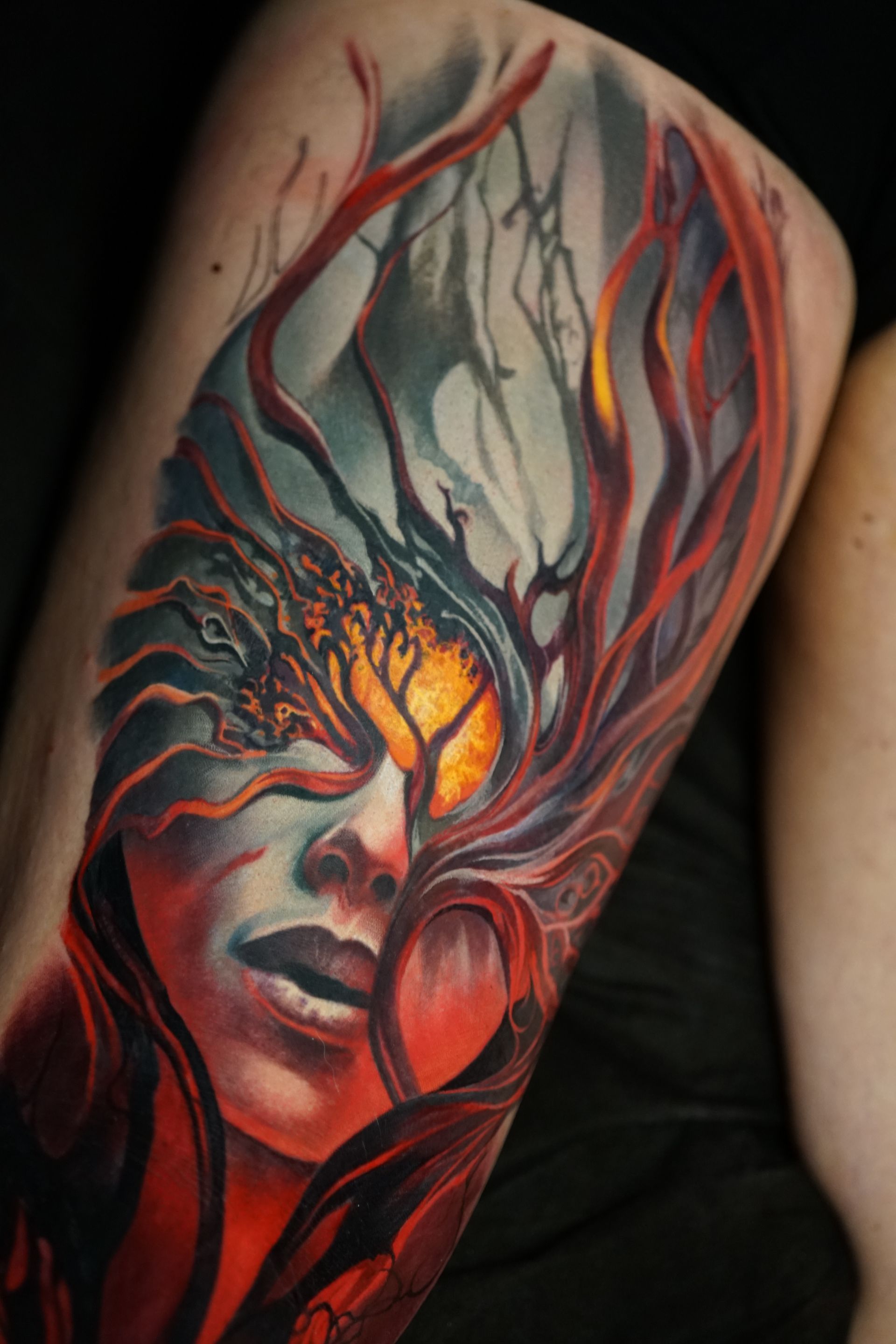 A woman has a colorful tattoo of a woman 's face on her leg.