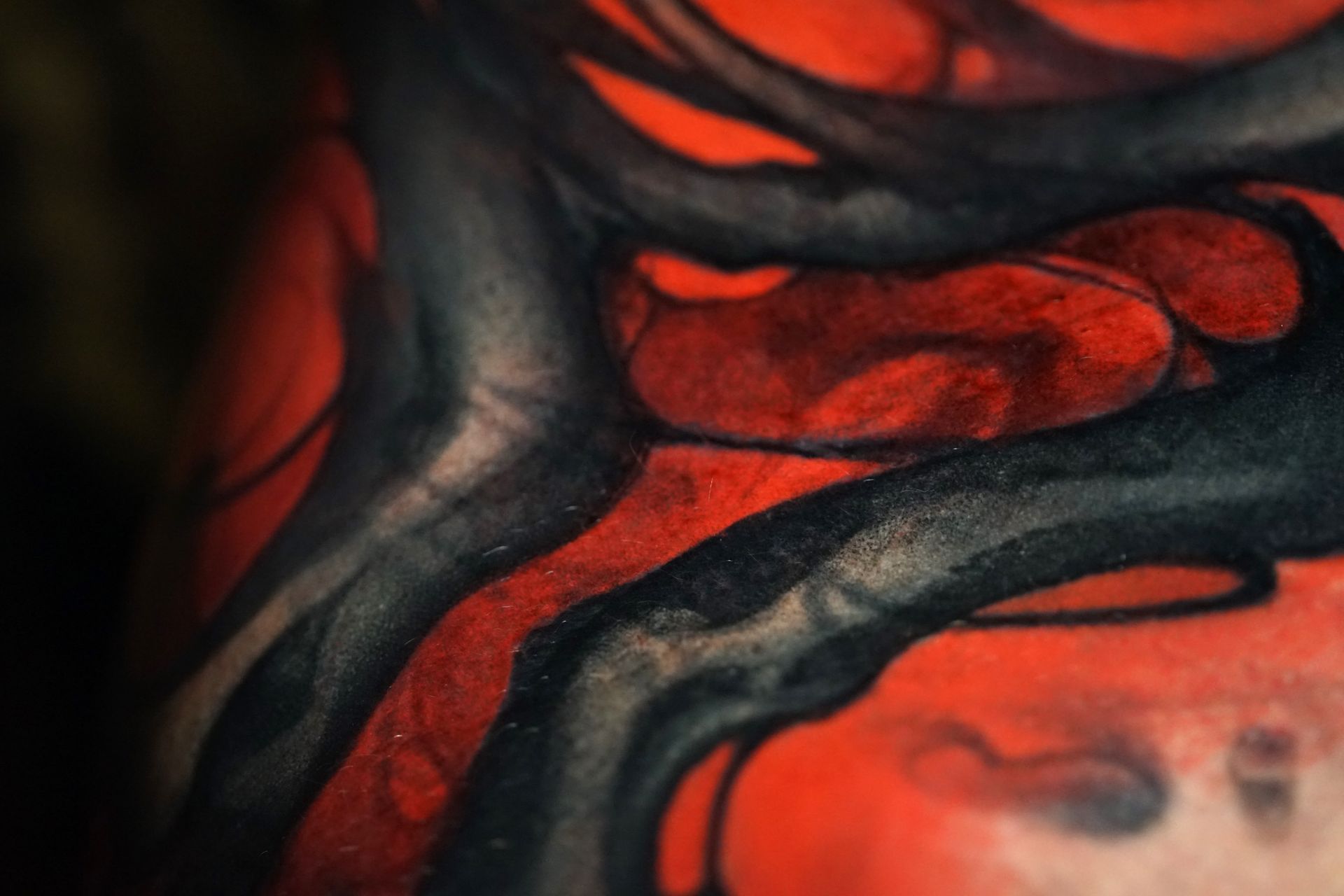 A close up of a red and black tattoo on a person 's arm.