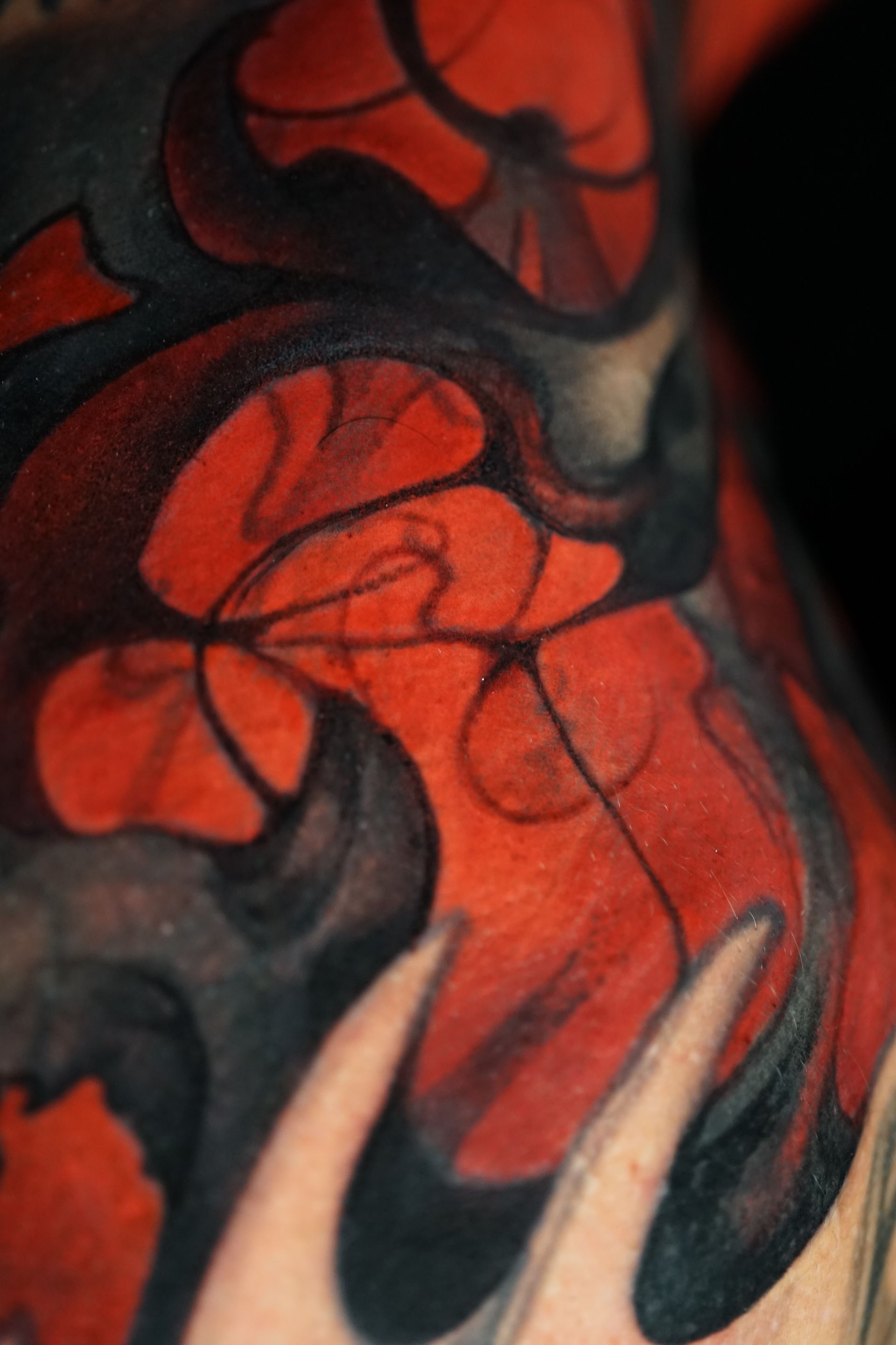 A close up of a red and black tattoo on a person 's arm.