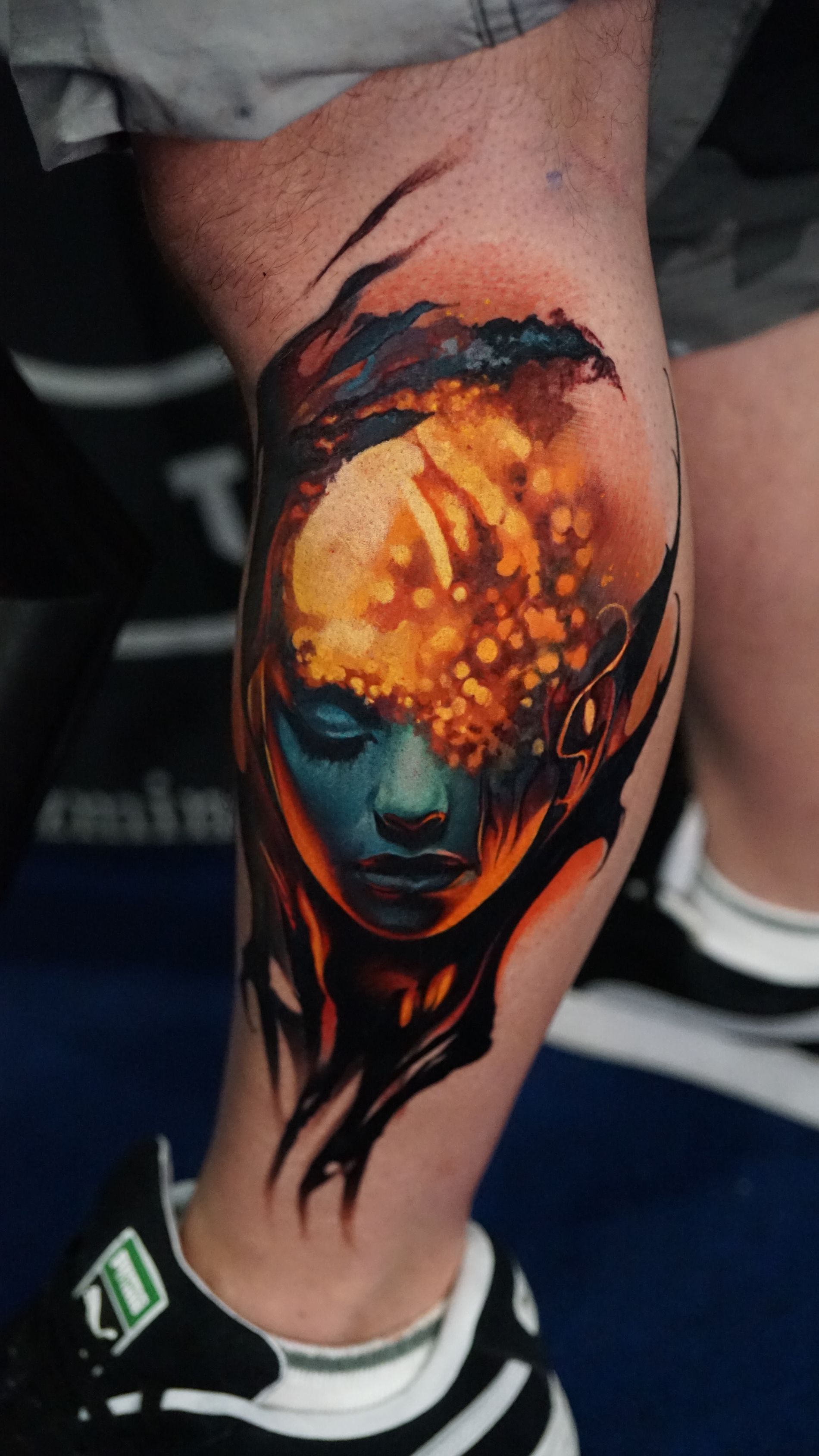 A person has a tattoo of a woman 's face on their leg.