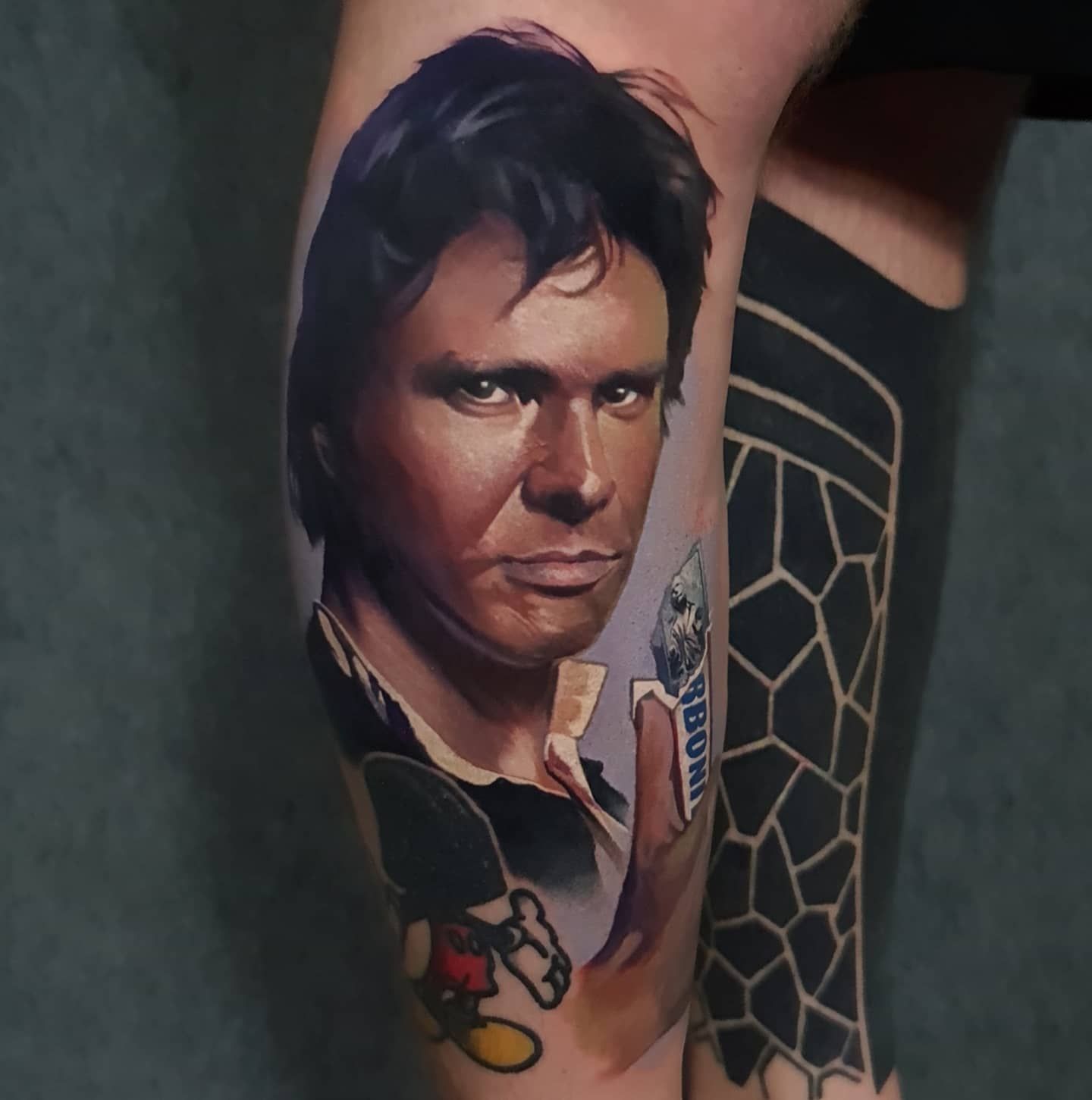 A man has a tattoo of han solo on his leg