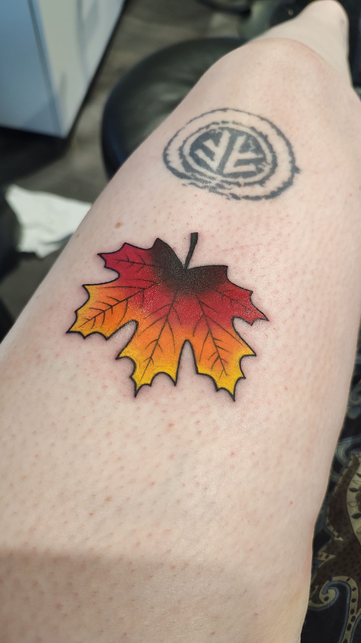 A person has a tattoo of a maple leaf on their leg.
